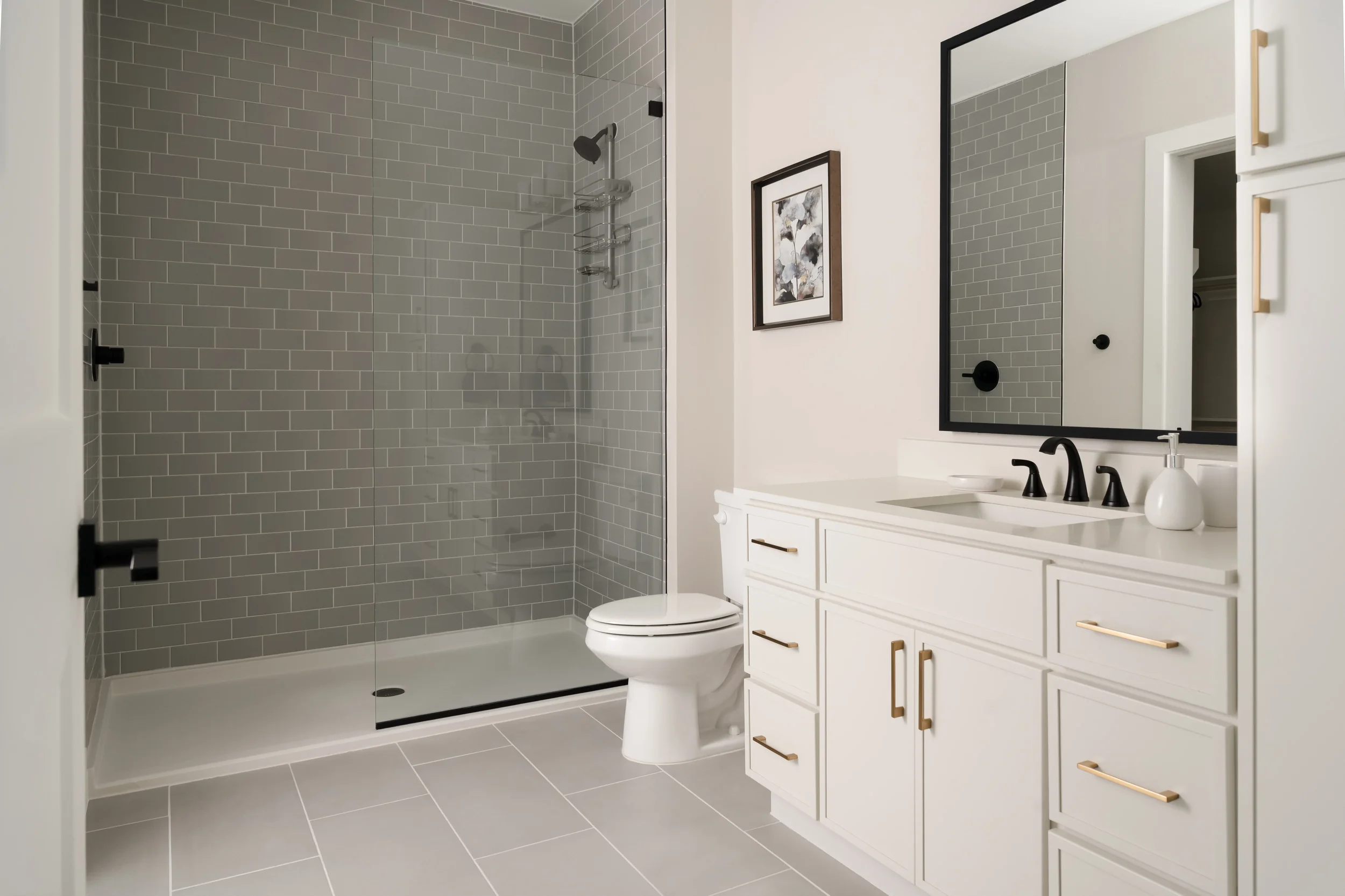 Model bathroom with gray tile shower and white vanity at The Platform in Frisco, TX. Designed by Artbuckle & Co.