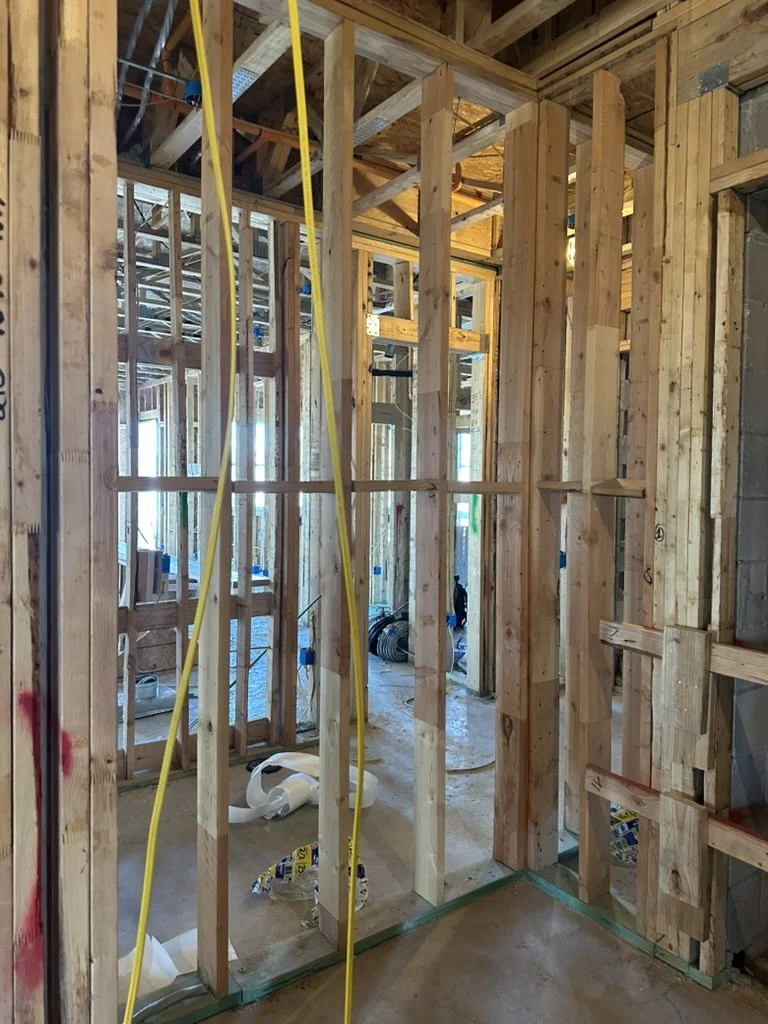 In-progress interior wood wall stud framing and yellow electrical conduit installation at Beacon in Frisco, TX, by Artbuckle & Co.