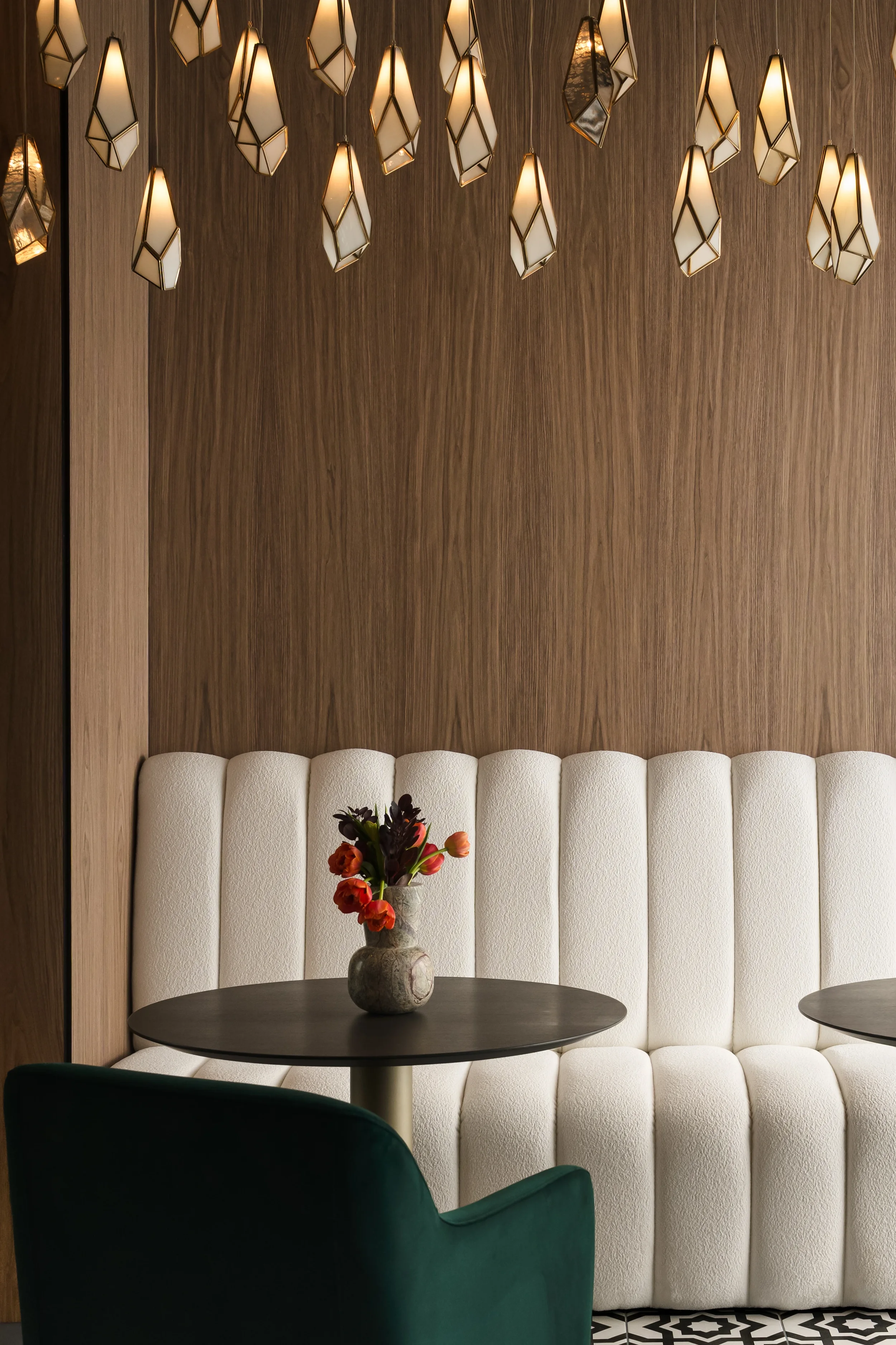 Cream banquette and walnut wall with faceted pendants at The Platform in Frisco, TX. Designed by Artbuckle & Co.