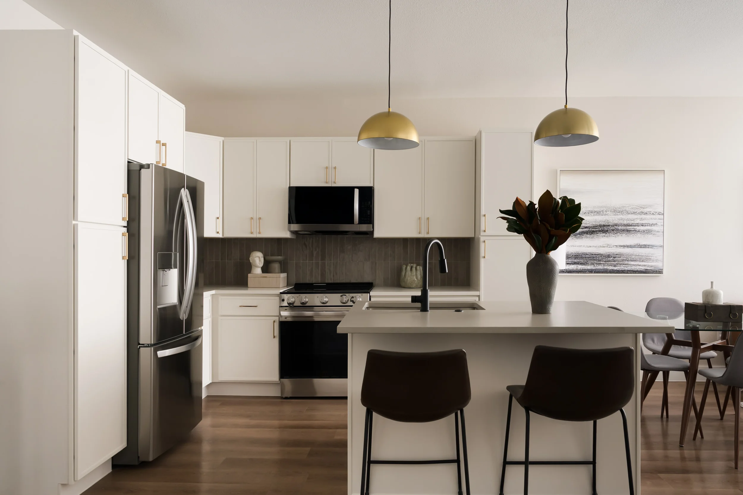 Model kitchen with white cabinets, brass pendant and black faucet at The Platform in Frisco, TX. Designed by Artbuckle & Co.
