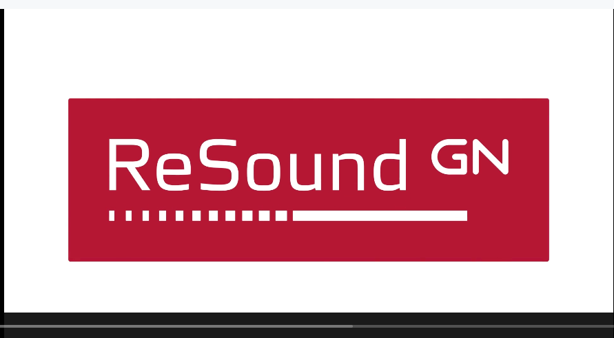 Waiting area with four black chairs, a green potted plant, a wall with beige and gray sections, and a tall floor lamp. A large flat-screen TV displays the Pixar film "Noisy Toys" with a robot and box character.