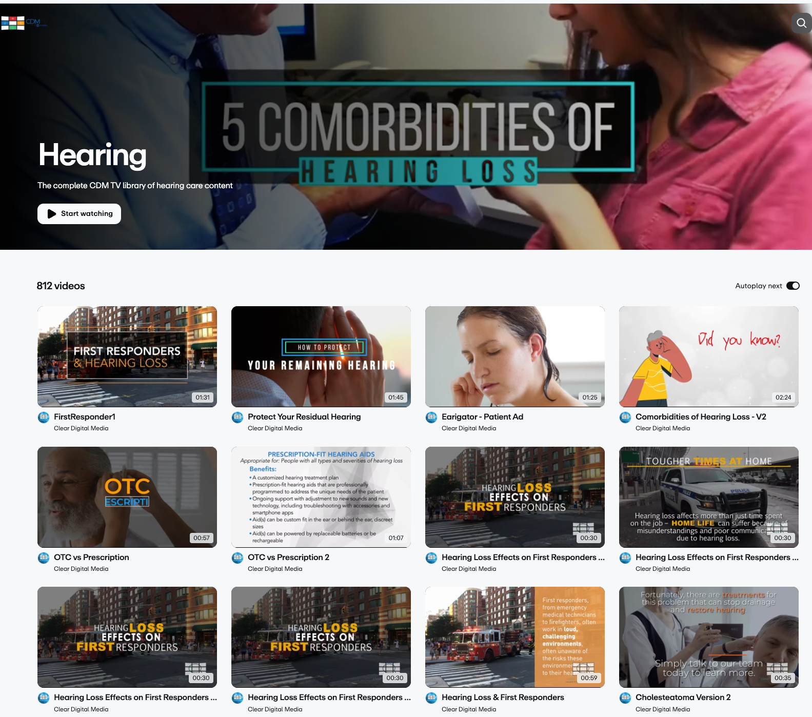 A lounge area with orange seating, a glass coffee table, and a wall-mounted TV displaying a woman wearing headphones, with green LED lighting around the TV.