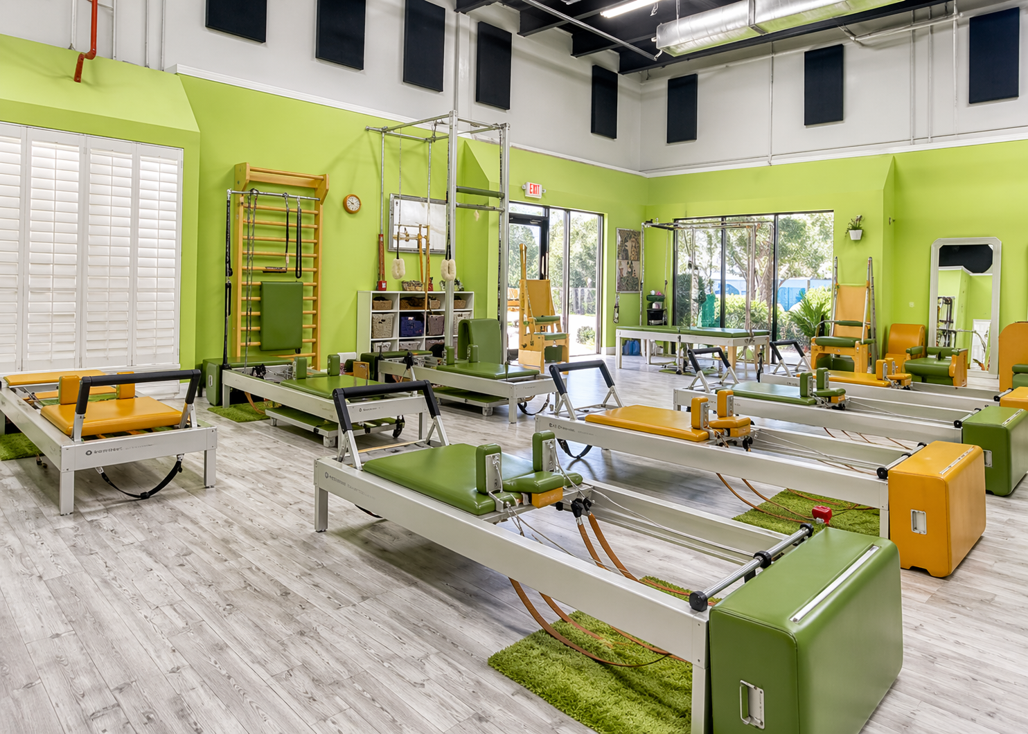 Indoor Pilates studio with green and orange reformer machines.