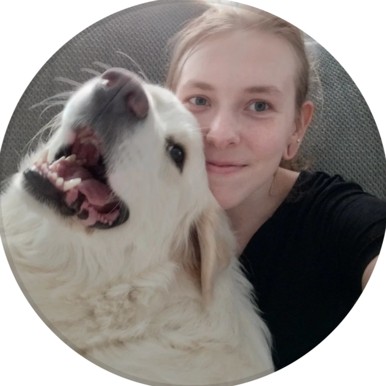 A woman taking a selfie with her dog, both smiling and close together interior setting.