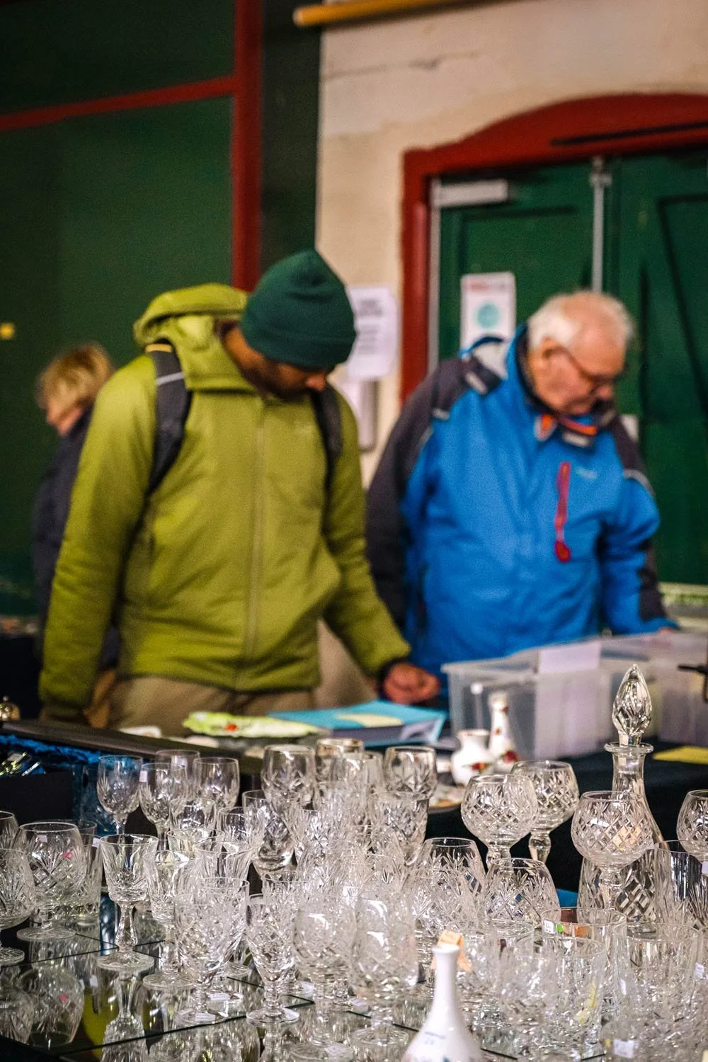 Two men browsing items on a stall at the Saturday Market in Brecon Market Hall in Powys.