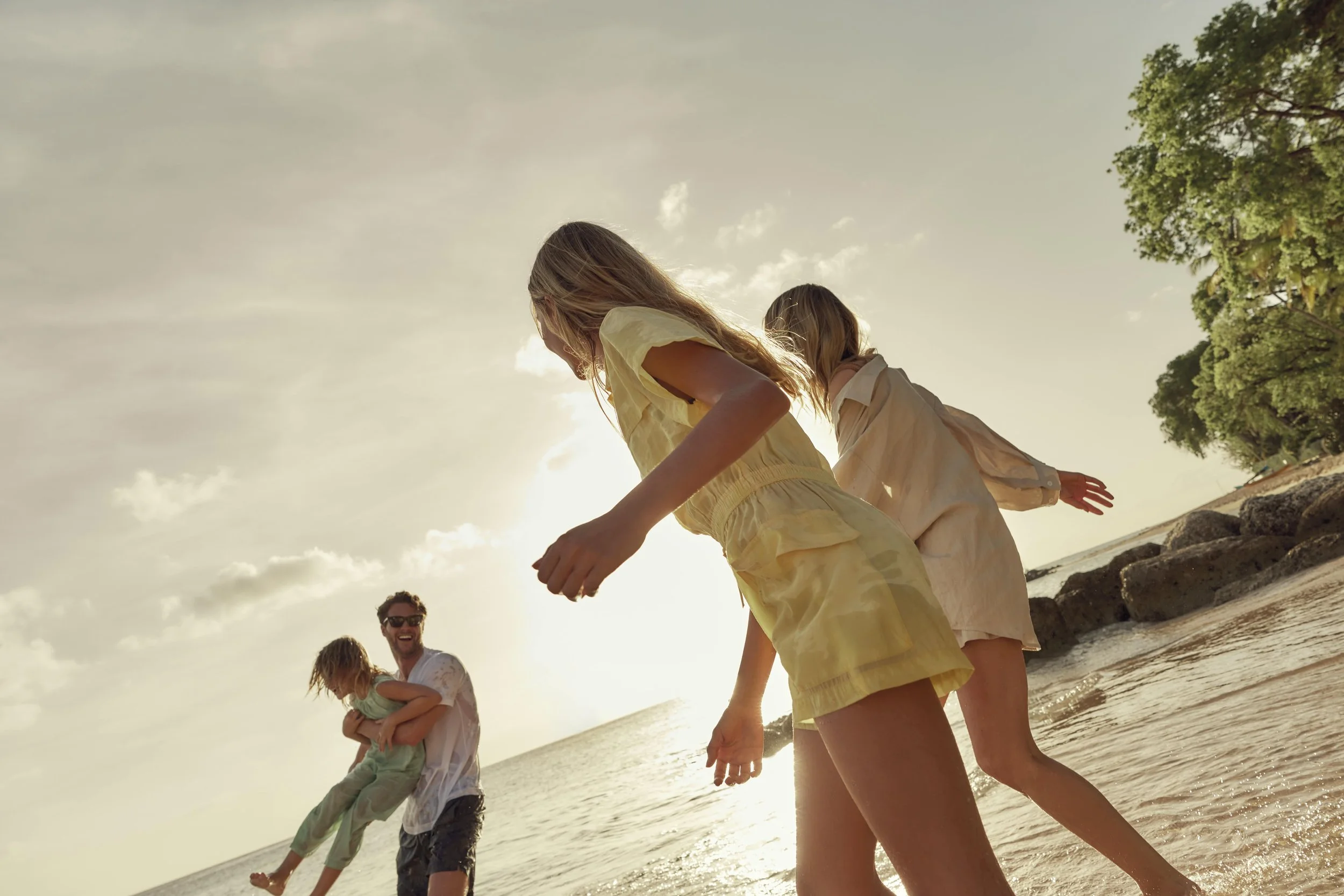 a family enjoying the beach at sunset, with children and adults playing in the shallow water