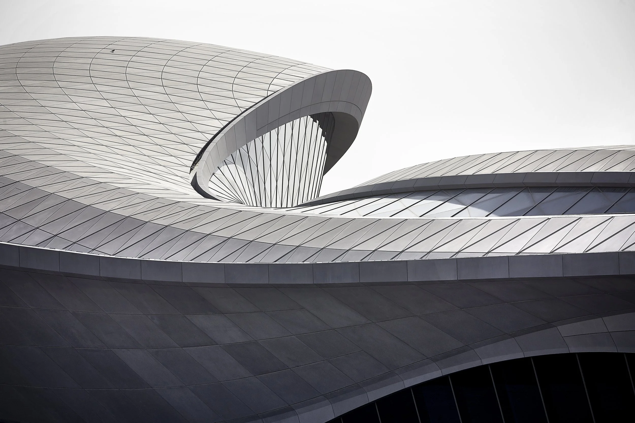 Close-up of a modern, futuristic building with sleek, curved metallic and glass surfaces.