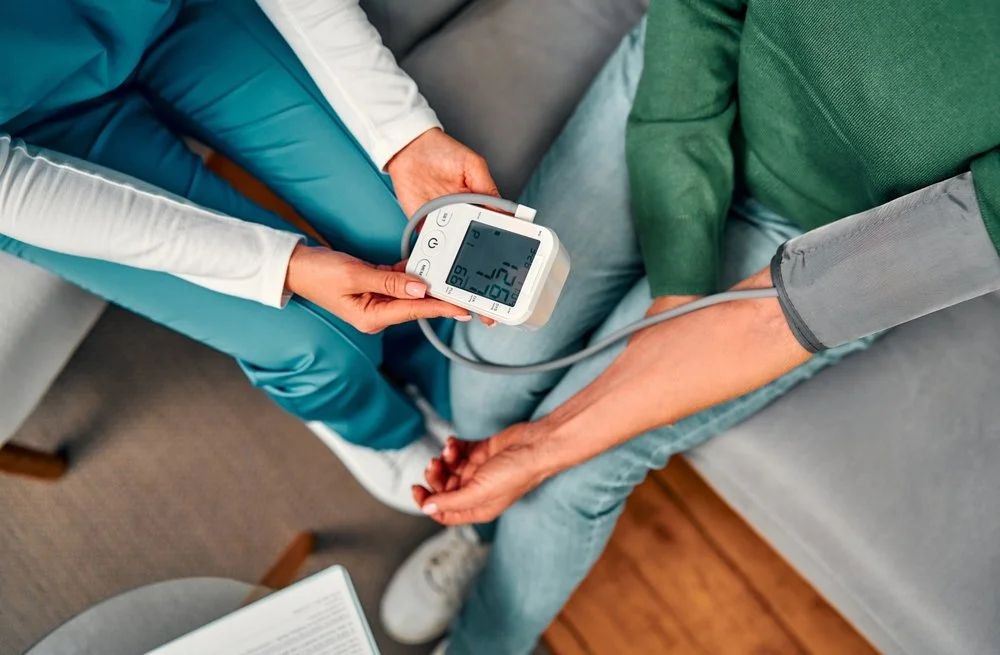 A healthcare professional taking a patient's blood pressure with a digital monitor in a medical setting.