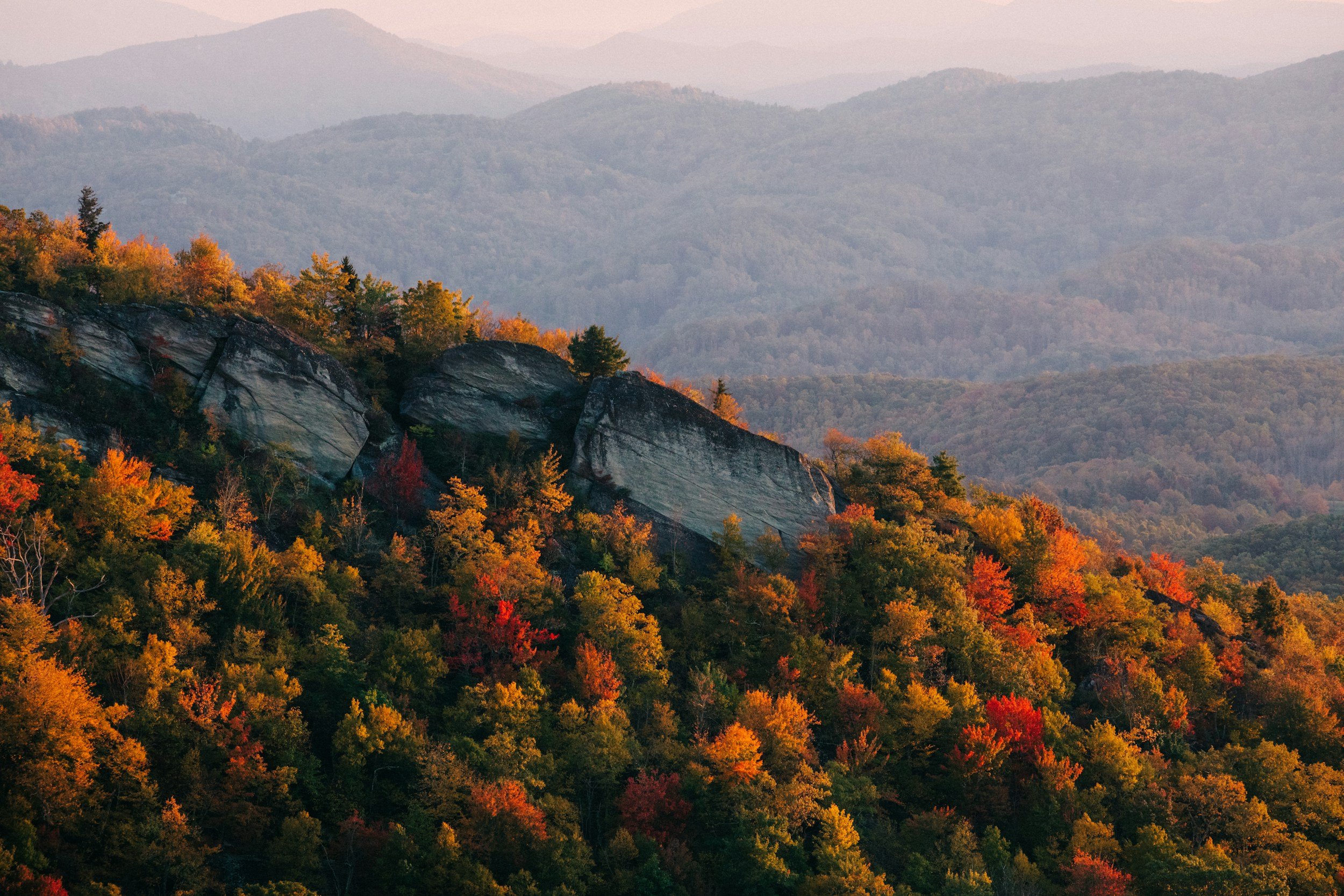 A mountain landscape with colorful fall foliage and layered mountain ranges in the distance.
