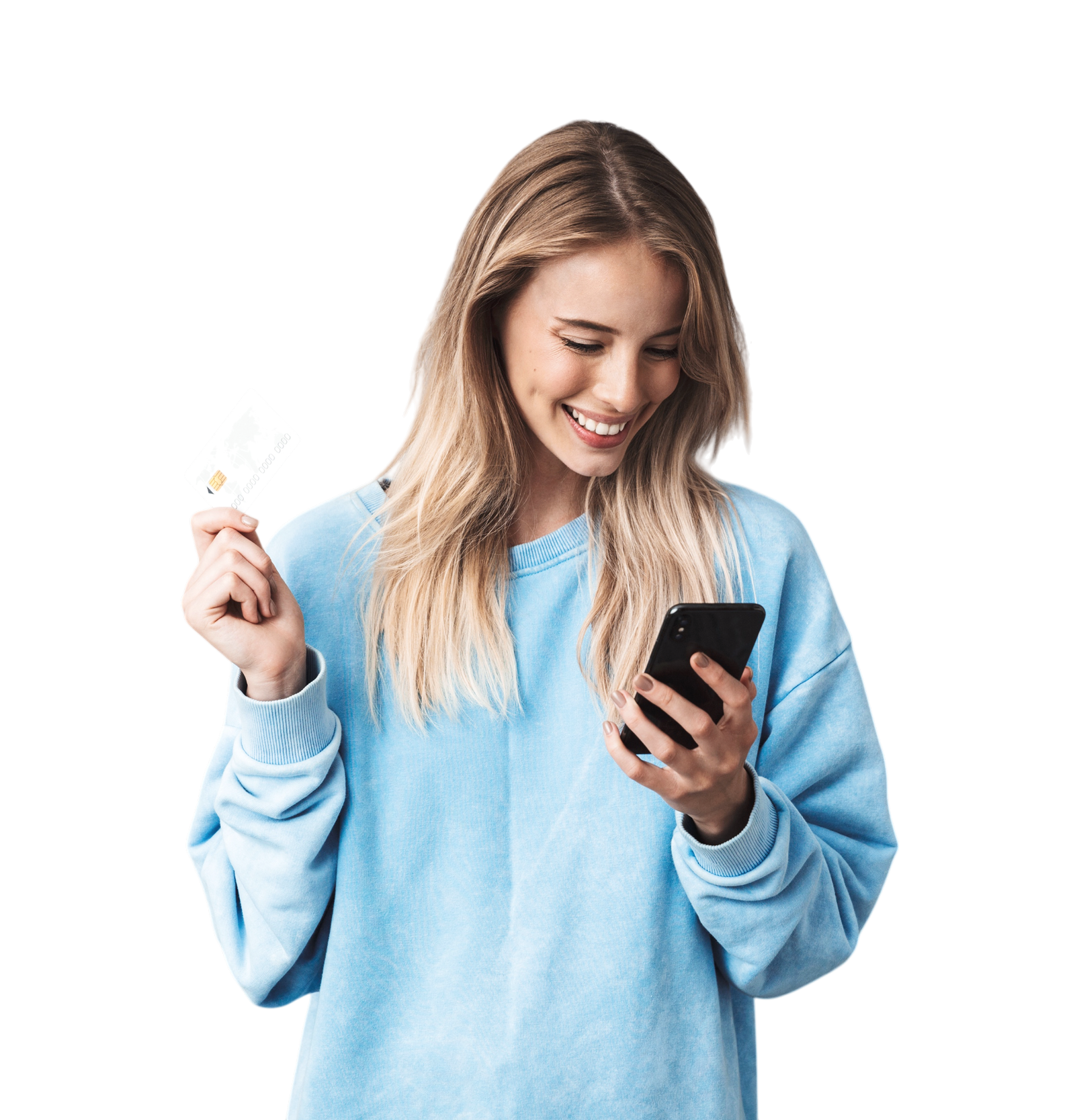 A young woman with long blonde hair wearing a light blue sweatshirt, holding a credit card in her left hand and a smartphone in her right hand, smiling while looking at her phone.