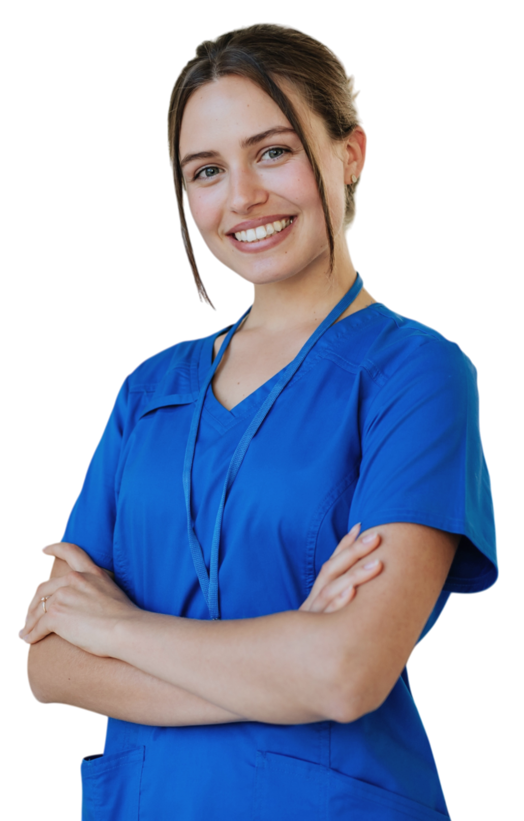 A woman with brown hair in a bun, wearing blue medical scrubs, smiling and standing with her arms crossed.
