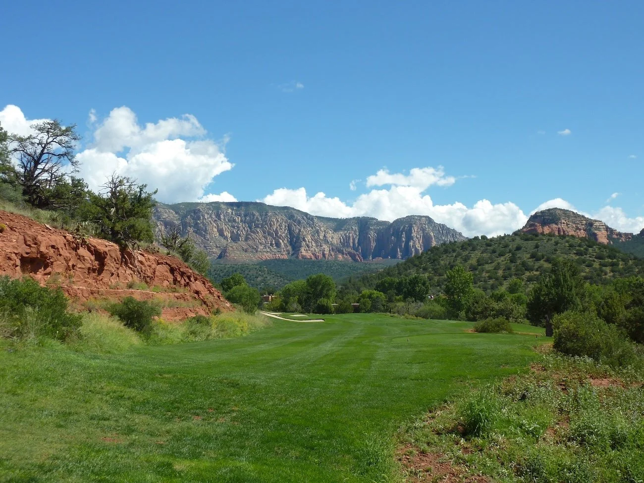 Scenic fairway view at Seven Canyons Golf Course surrounded by mountains and red rock cliffs