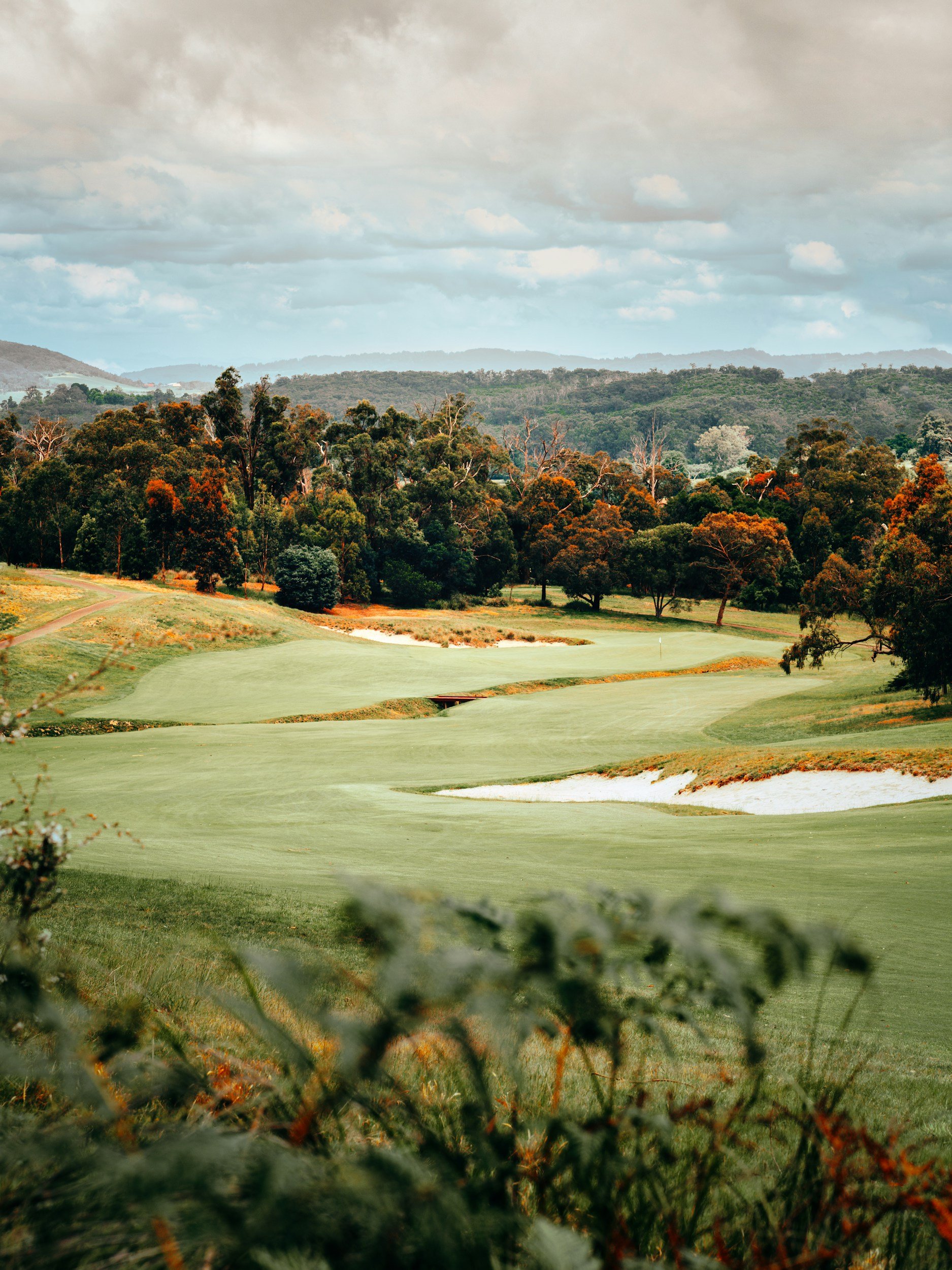Autumn golf course scene with a narrow creek crossing the fairway between bunkers