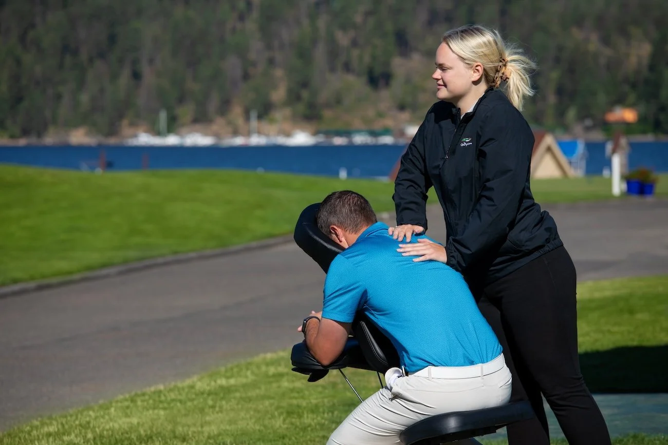 A Coeur d’Alene Resort therapist massages a golfer’s upper back and shoulders in an outdoor chair session at the course.