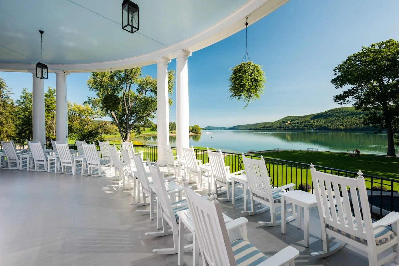 Two rows of rocking chairs on the Otesaga Resort Hotel's veranda, facing the lake.