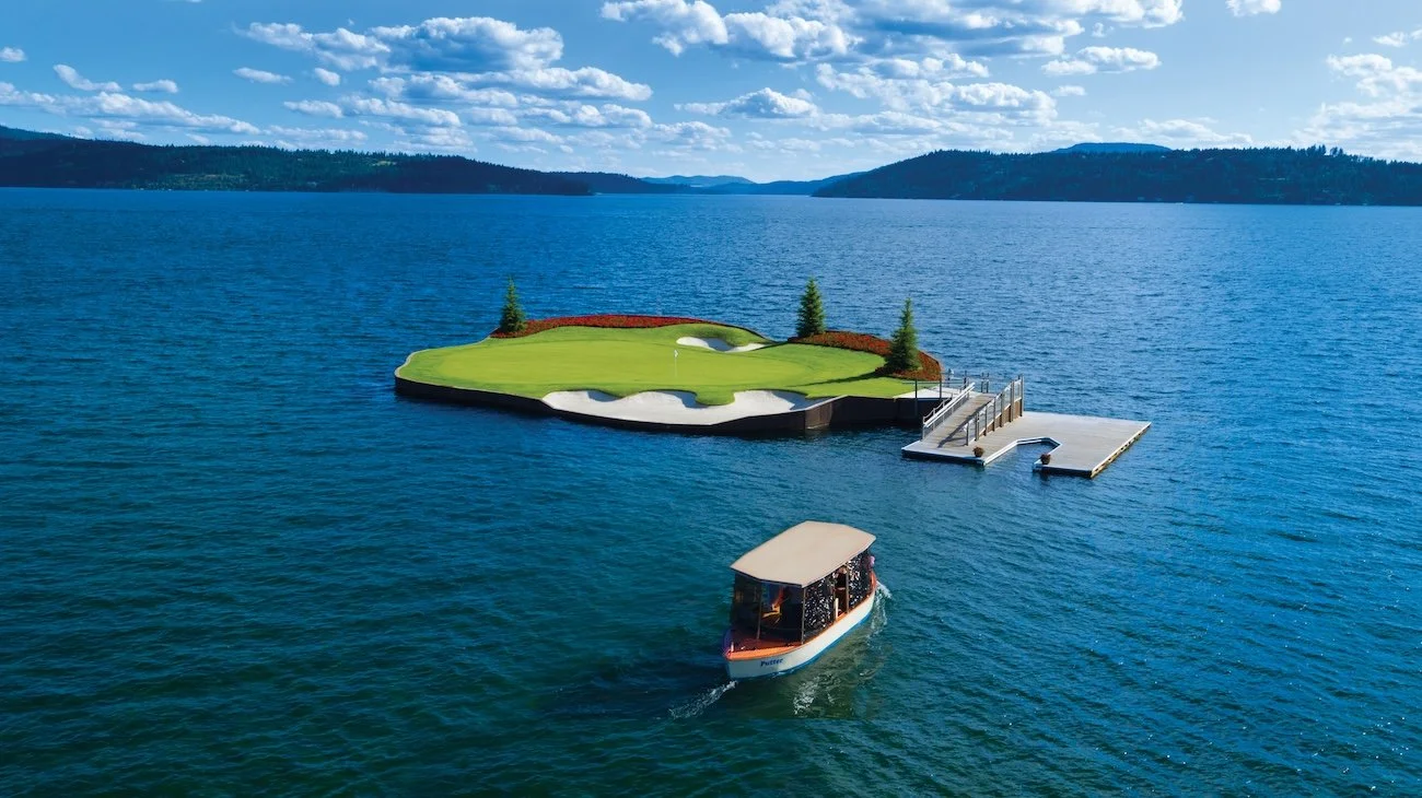 Small boat heading away from the floating island green and dock in Lake Coeur d’Alene.