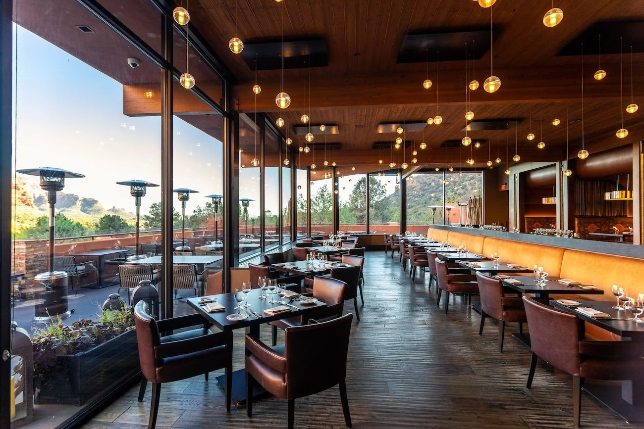 Floor-to-ceiling windows and the outdoor dining terrace at Enchantment Resort restaurant showcase sweeping red rock views of Boynton Canyon