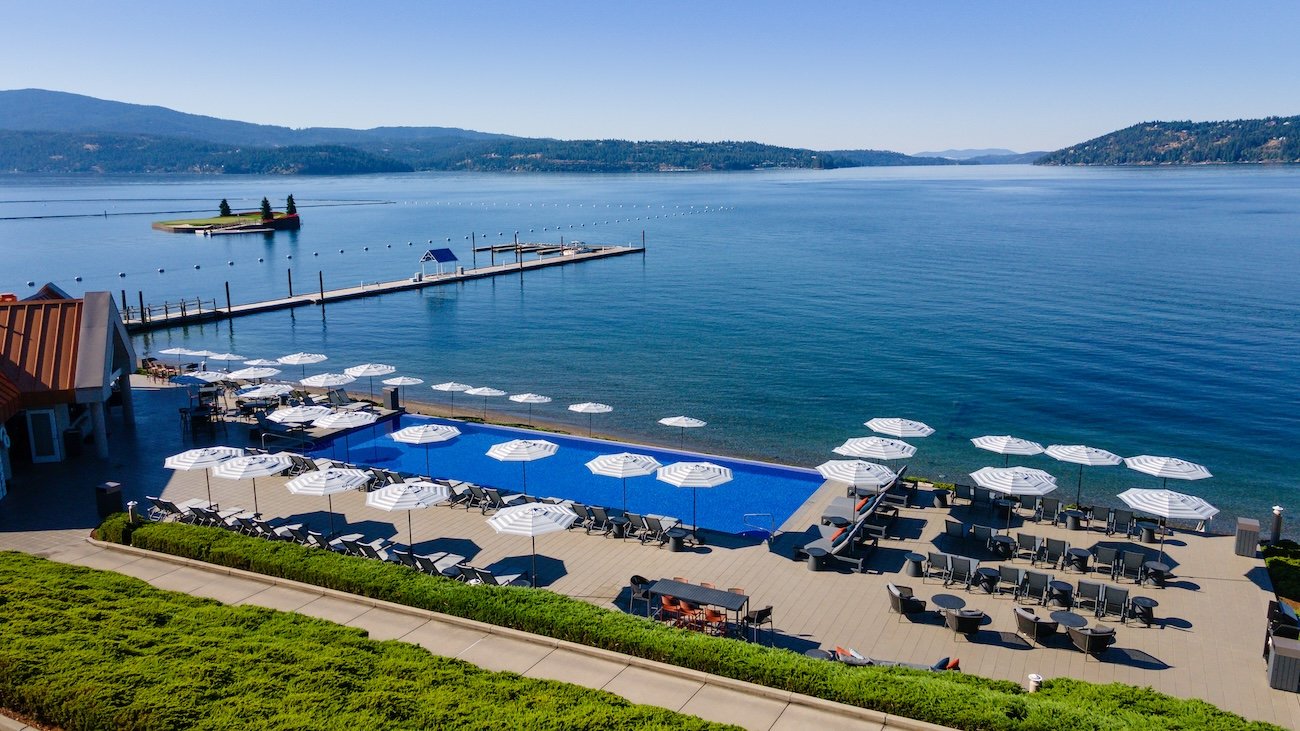Infinity-edge pool overlooking Lake Coeur d’Alene with the resort dock and floating island green in the distance.