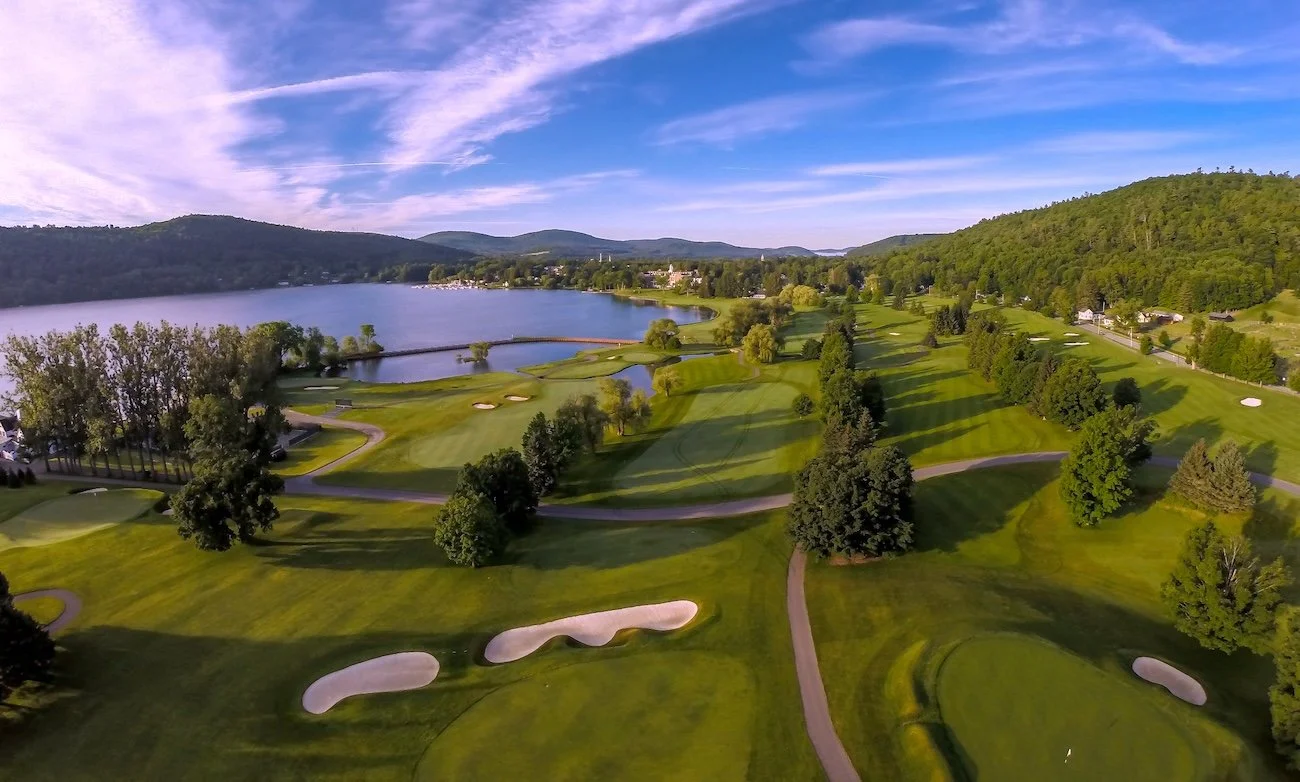 Aerial view of Leatherstocking Golf Course, fairways separated by trees, some holes running along Lake Otsego.