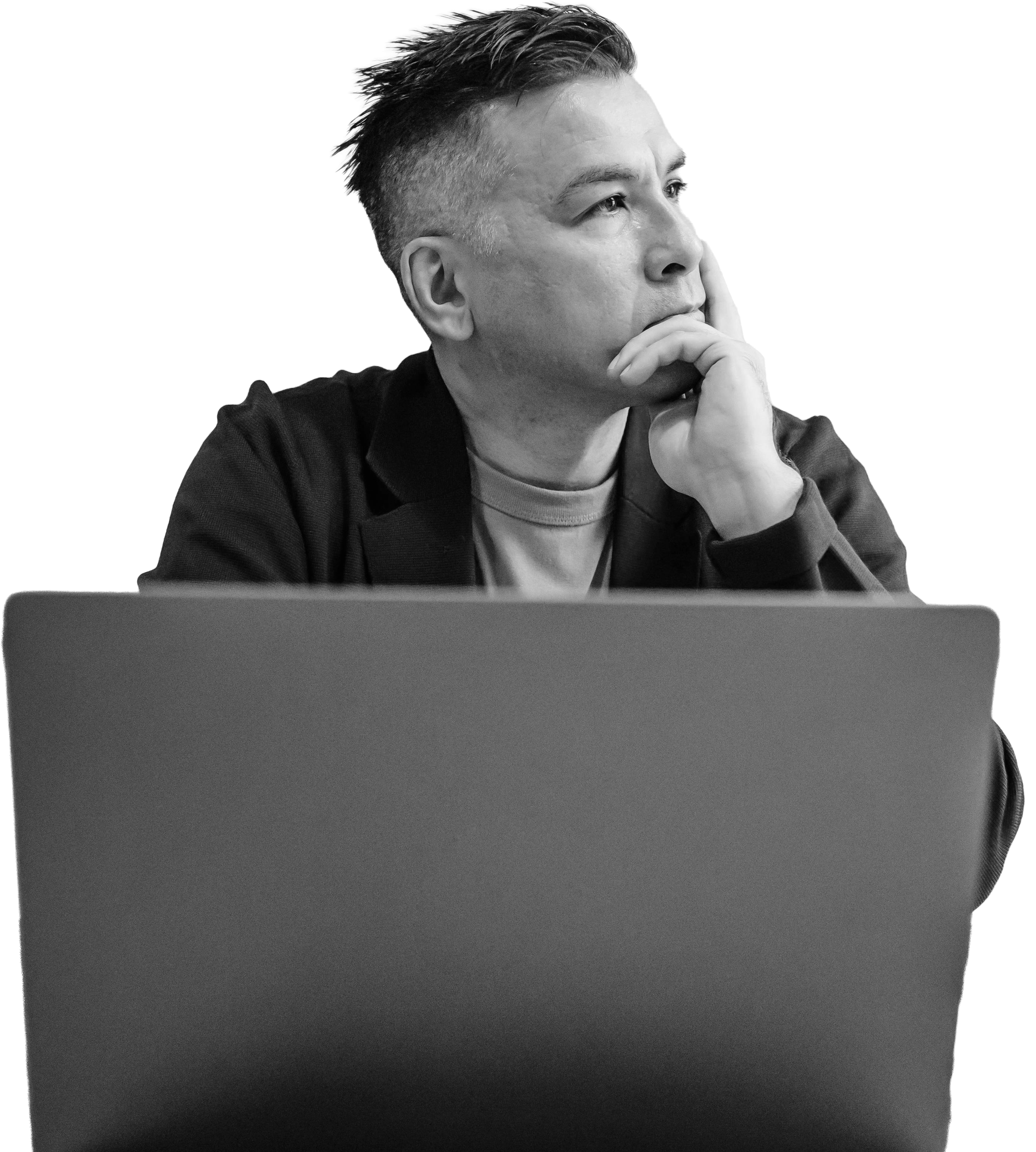 A person sitting behind a laptop, resting their chin on their hand, looking thoughtfully to the side.