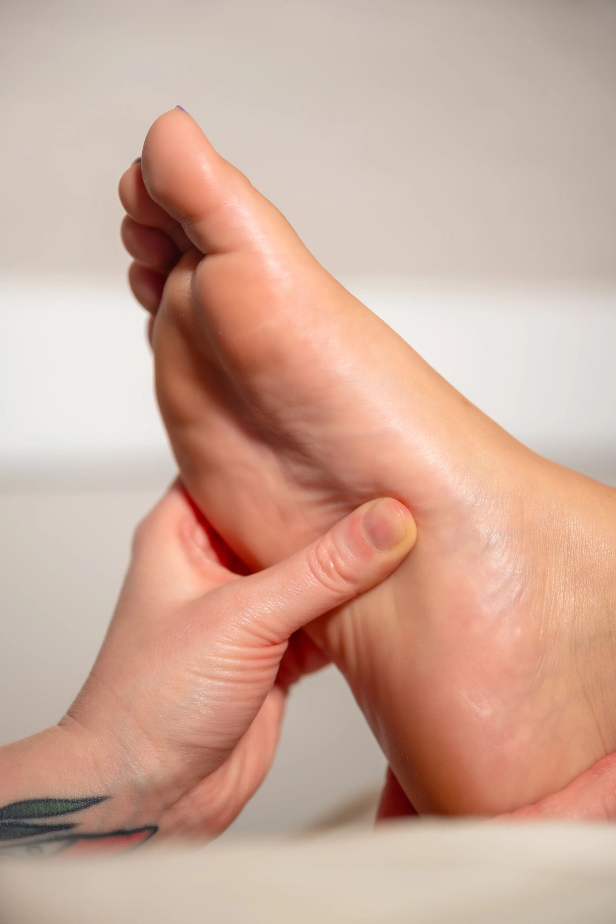 A person holding their foot with one hand, showing the sole and heel.