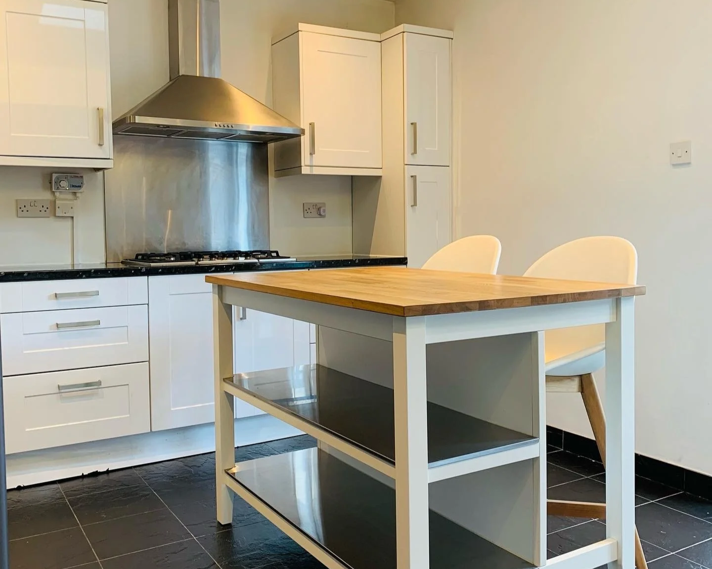 A before image of black and white kitchen with an island in the middle. The kitchen is bare