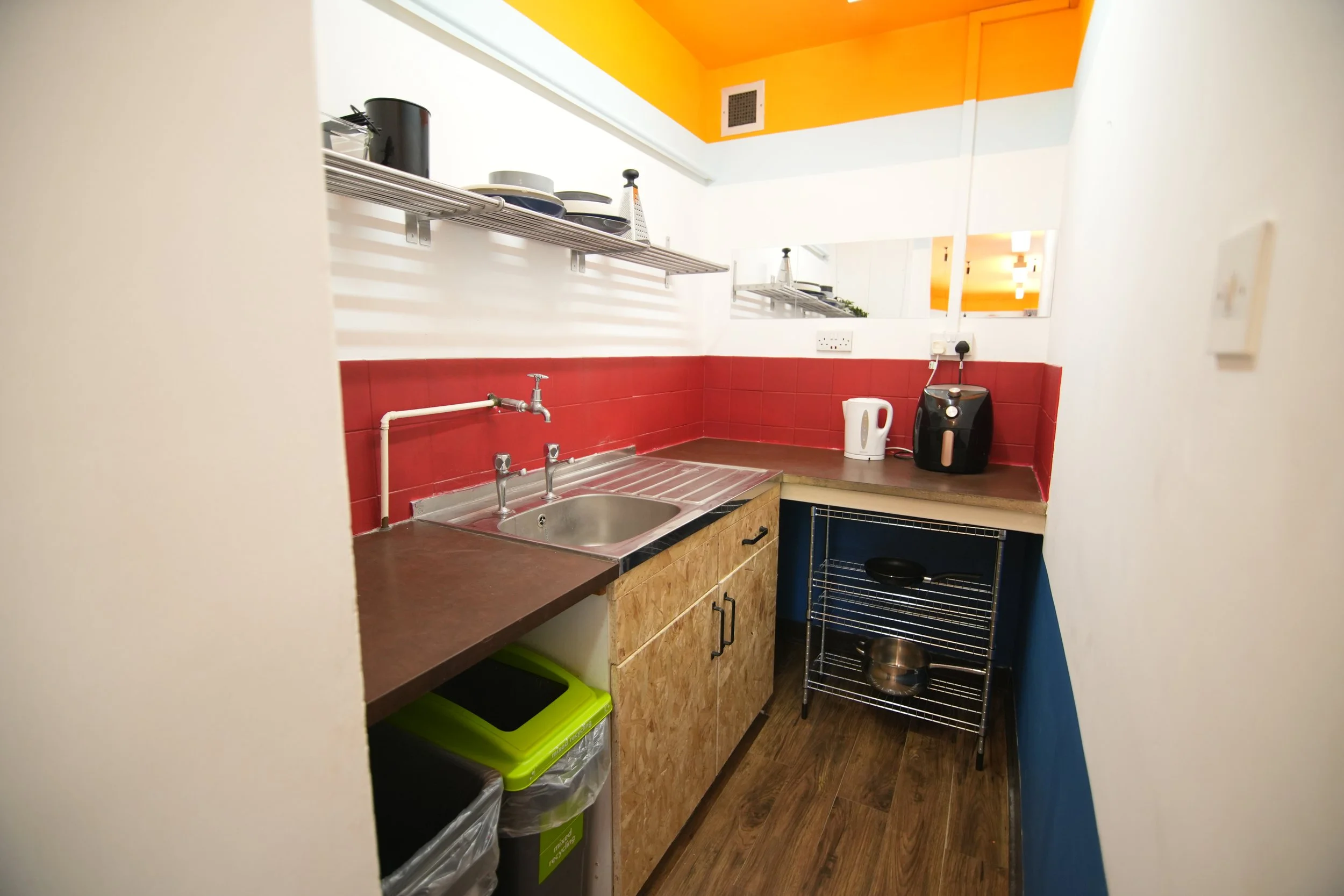 The original kitchen prep area received mostly a decorative update with new functional storage pieces. Difficult to encourage greater social interaction beyond 2 people, the kitchen is extended out into the main mess deck area, however, mirrors on th