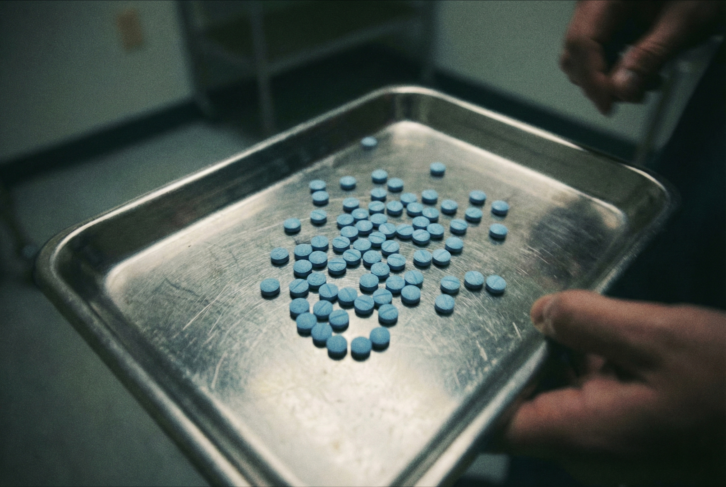 Pilules bleues sur un plateau en inox, illustrant l'effet anesthésiant du bleu corporatif (banques, réseaux sociaux).