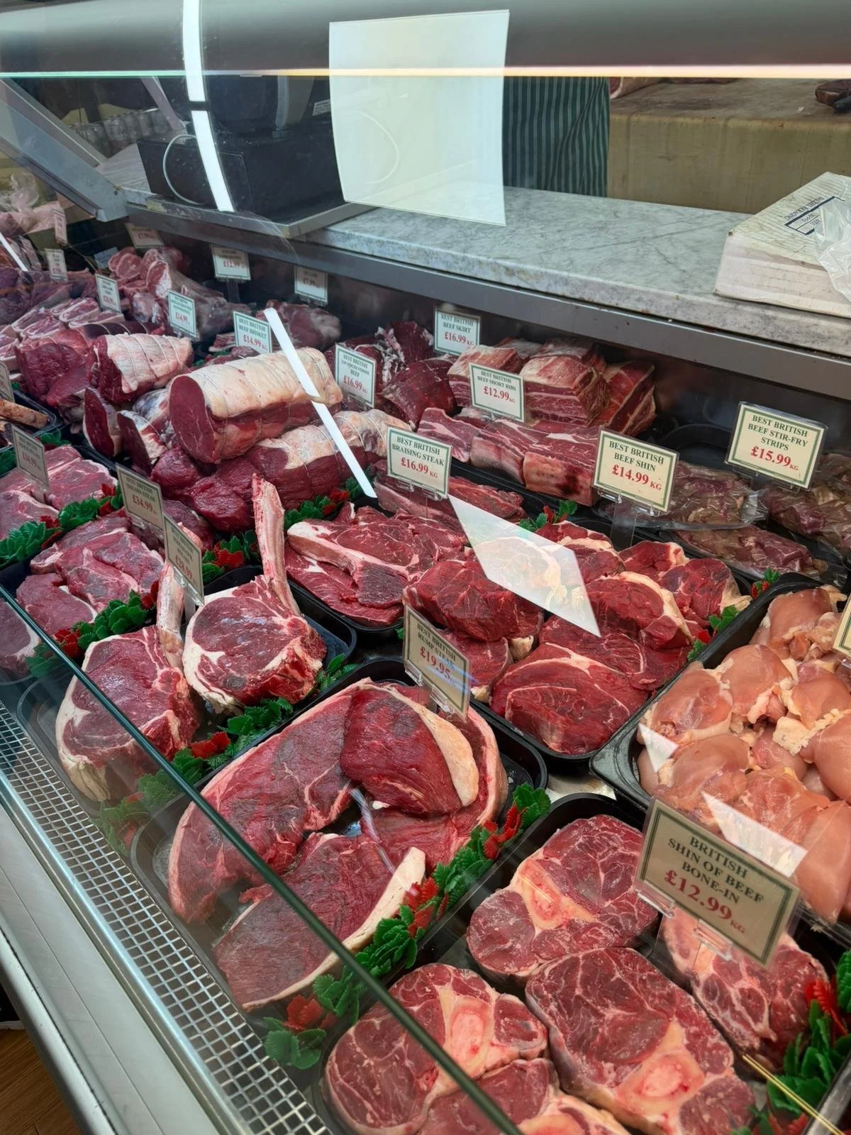 Display case with various cuts of raw beef in a butcher shop.