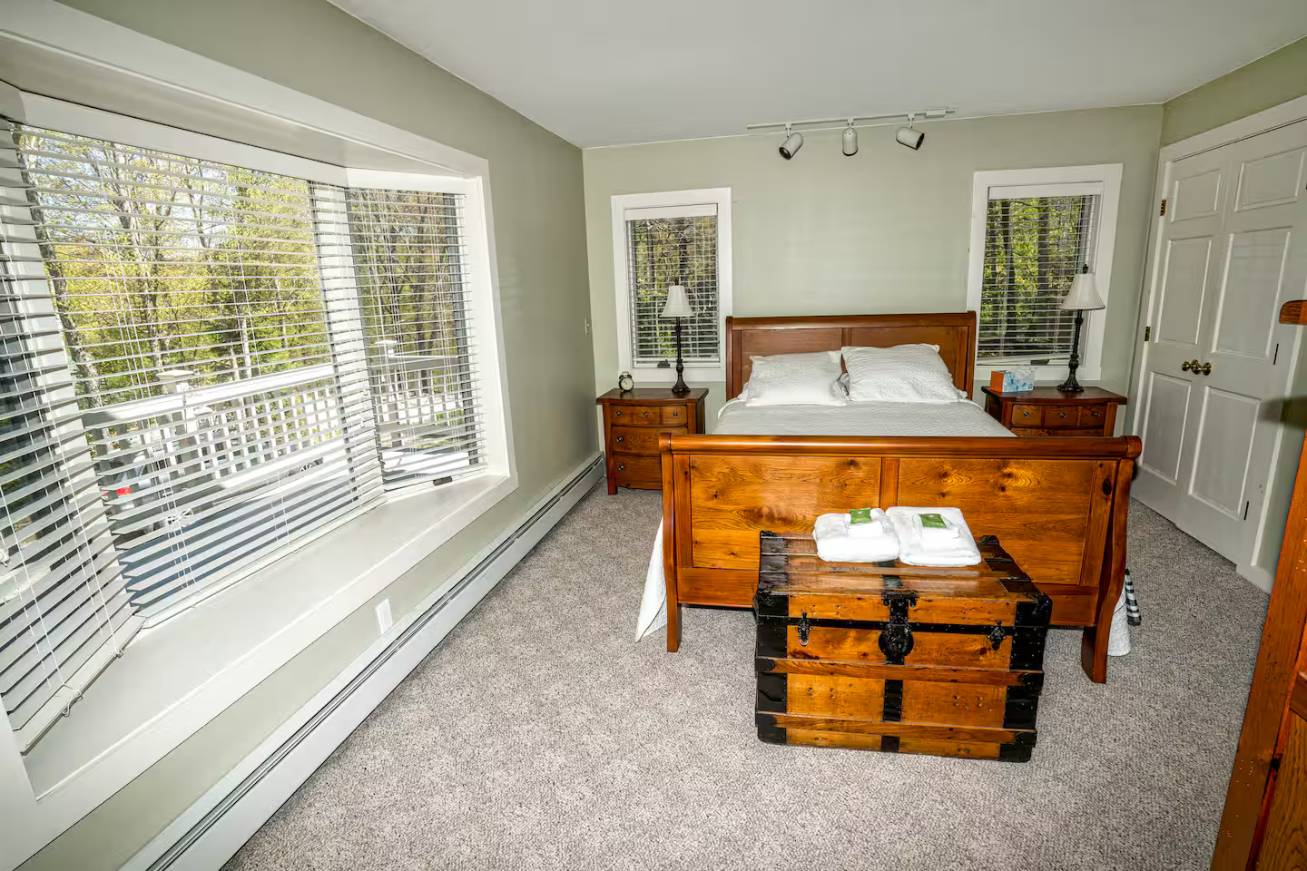 Bedroom 1 – Primary Suite
Queen bed | Main floor | Private en-suite bathroom
Your peaceful retreat with large windows framing views of the surrounding forest, a walk-in shower bathroom, and flat-screen TV.