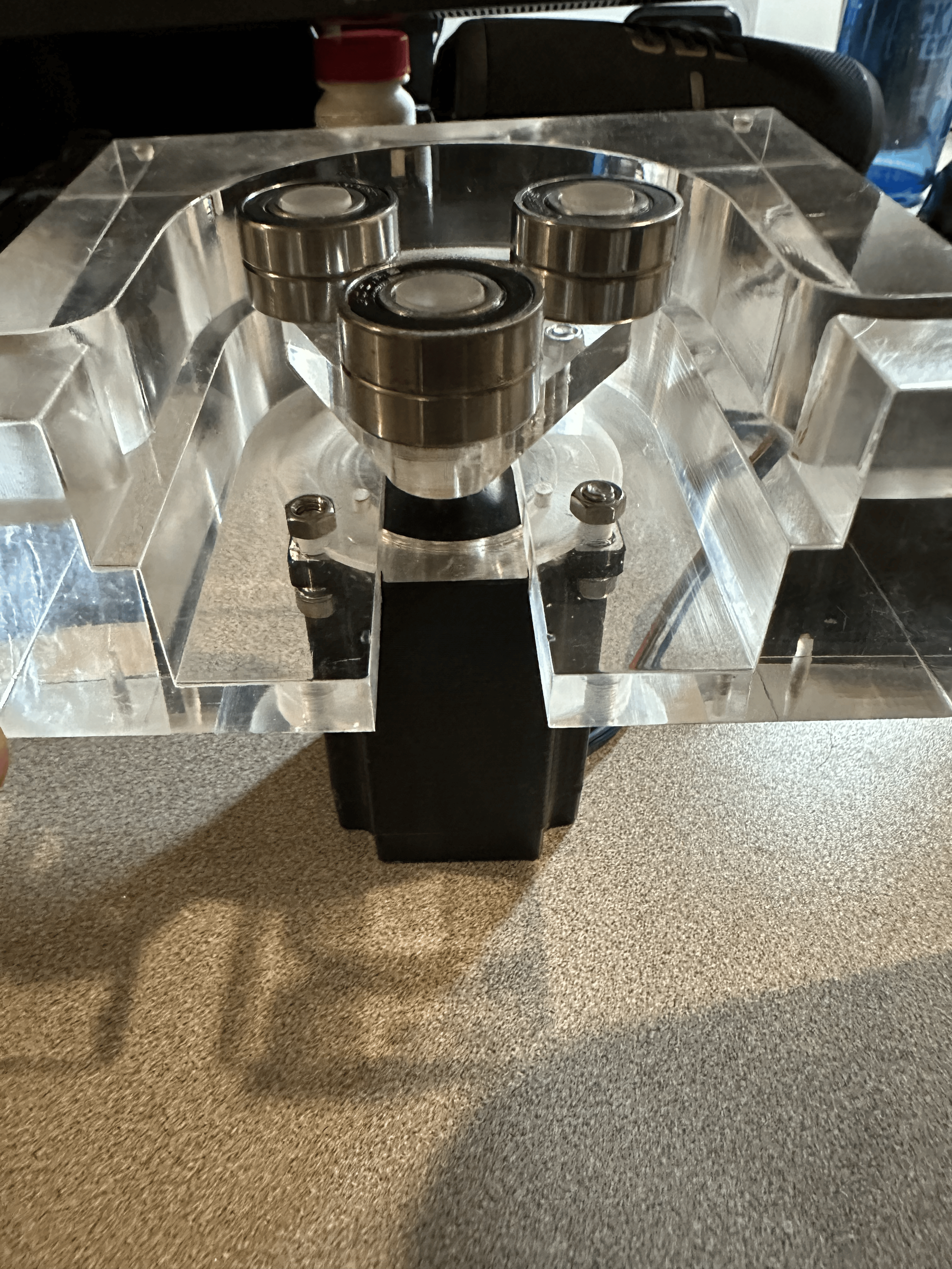 A machine with a clear acrylic top and three metal rollers inside.