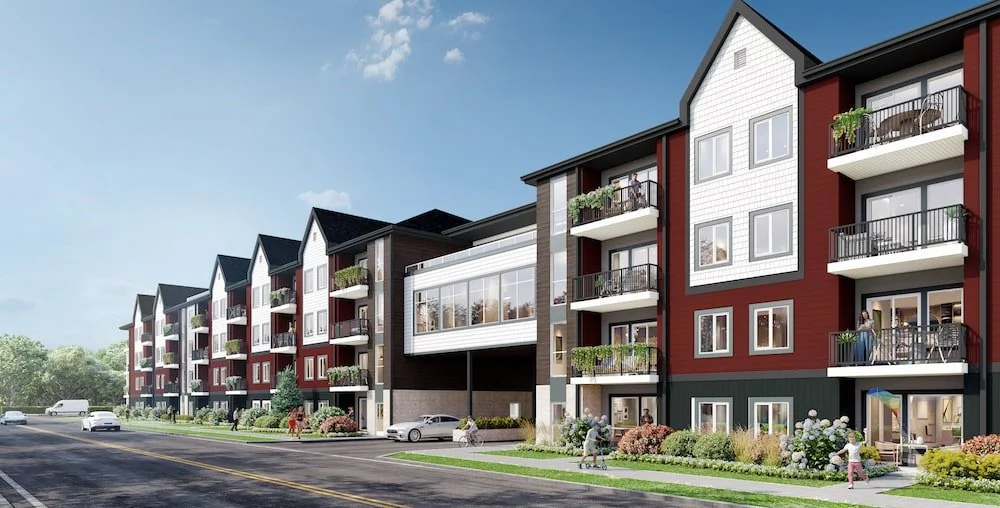 A modern multi-story apartment complex with balconies, trees, and parked cars along a street under a blue sky.