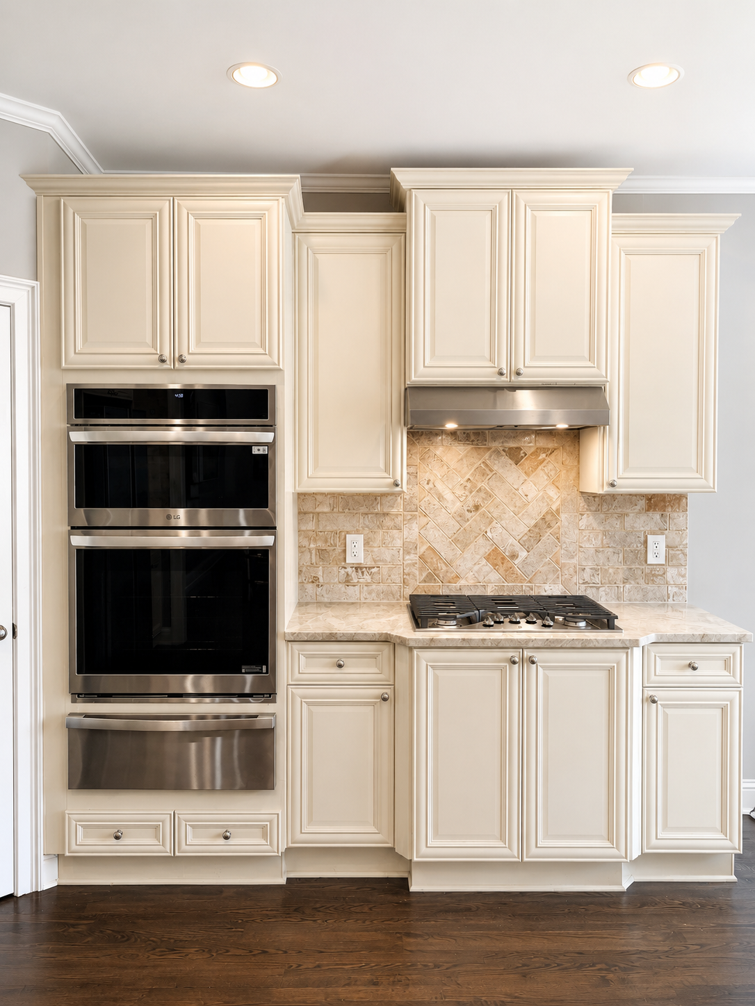 Kitchen with cream-colored cabinets, a built-in stainless steel oven, a gas stove with a stainless steel hood, and a beige tile backsplash.