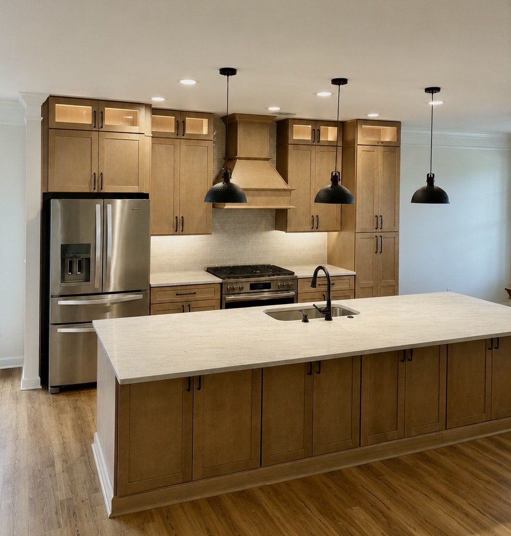 Modern kitchen with wooden cabinets, stainless steel refrigerator, black pendant lights, and light-colored island countertop.