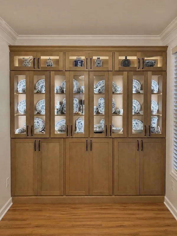 A wooden china cabinet filled with blue and white patterned dishes.