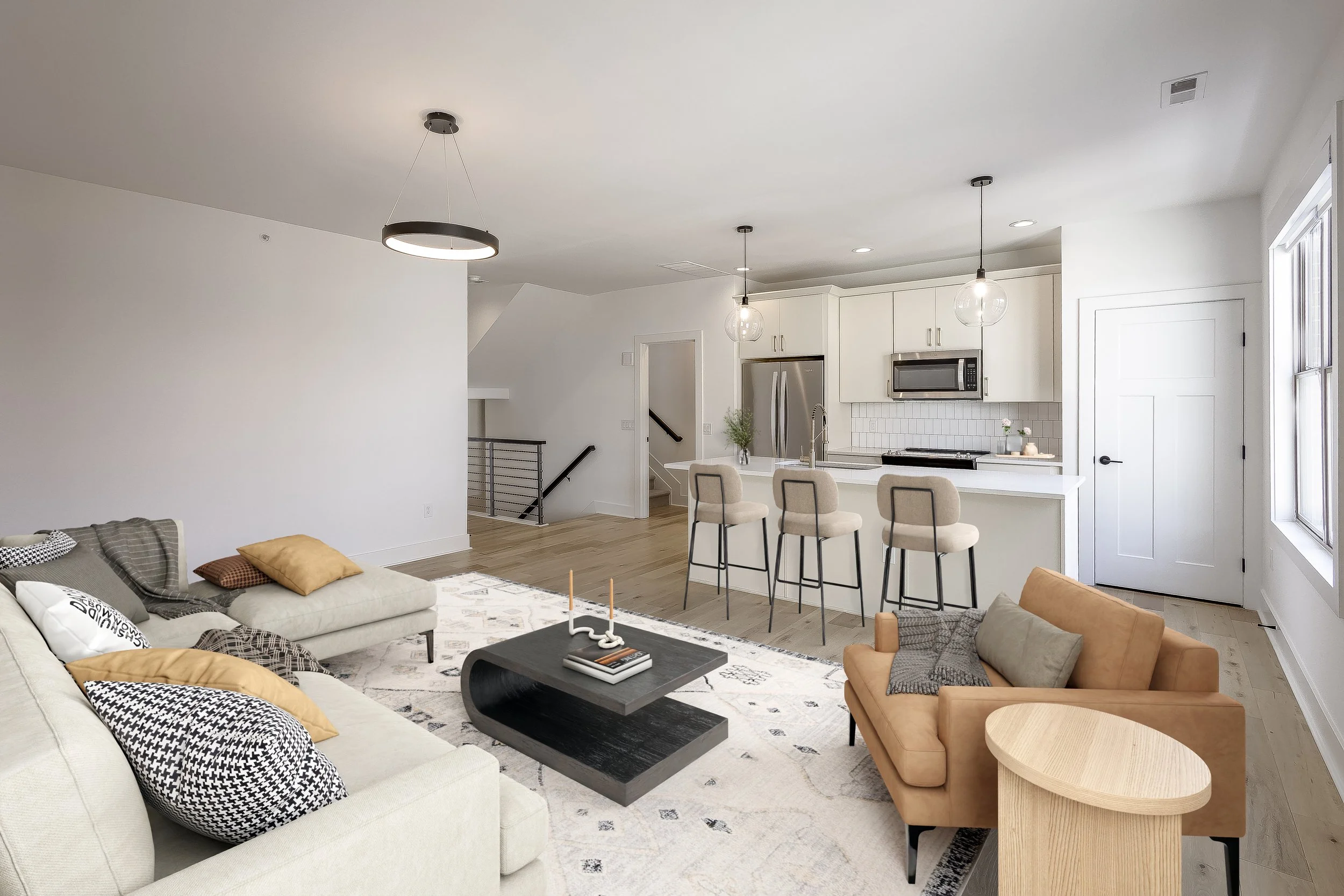 Modern open-concept living room and kitchen with white cabinetry, pendant lights, and a neutral color palette.