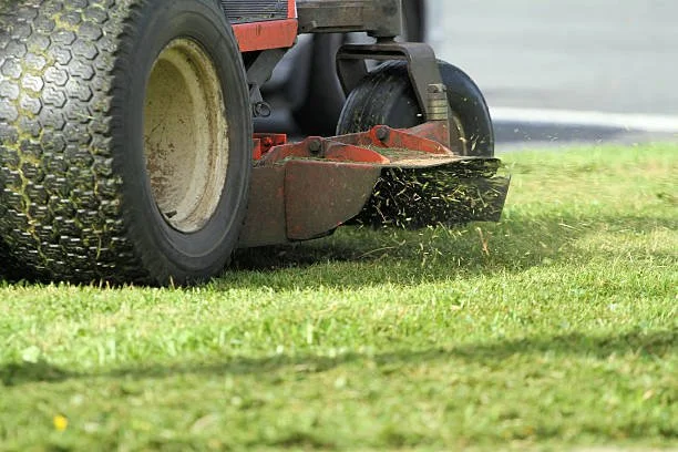 A red riding lawn mower cutting grass on a lawn.