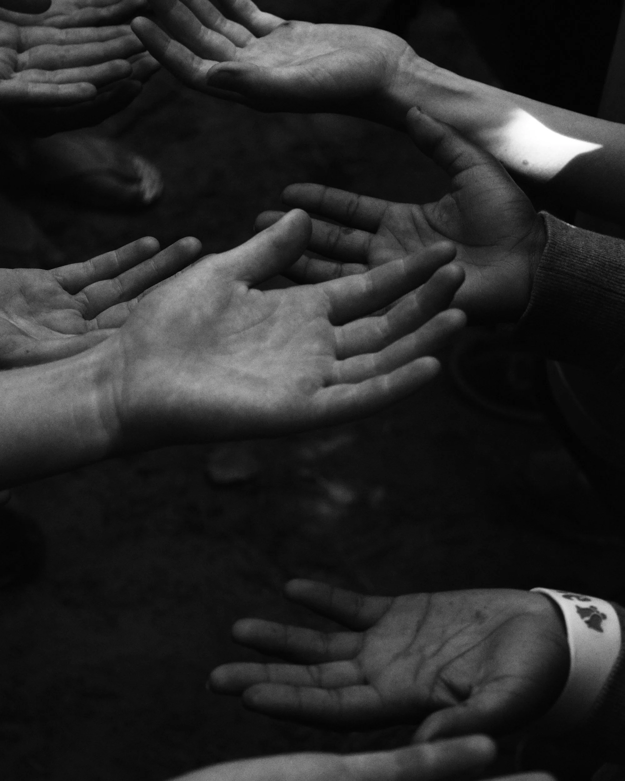 Multiple hands reaching out towards each other, creating a sense of connection and unity, in black-and-white.
