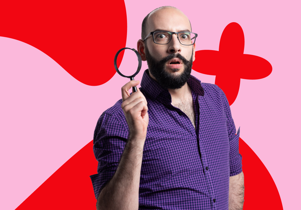 A person with glasses, a beard, and a surprised expression holding a magnifying glass, standing against a colorful abstract background of red and pink shapes.