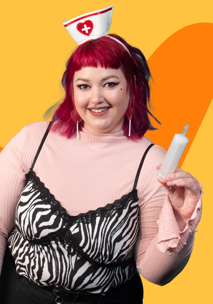 A person with bright pink hair holding a syringe, wearing a nurse hat, pink top, and zebra print dress, with an orange and yellow background.