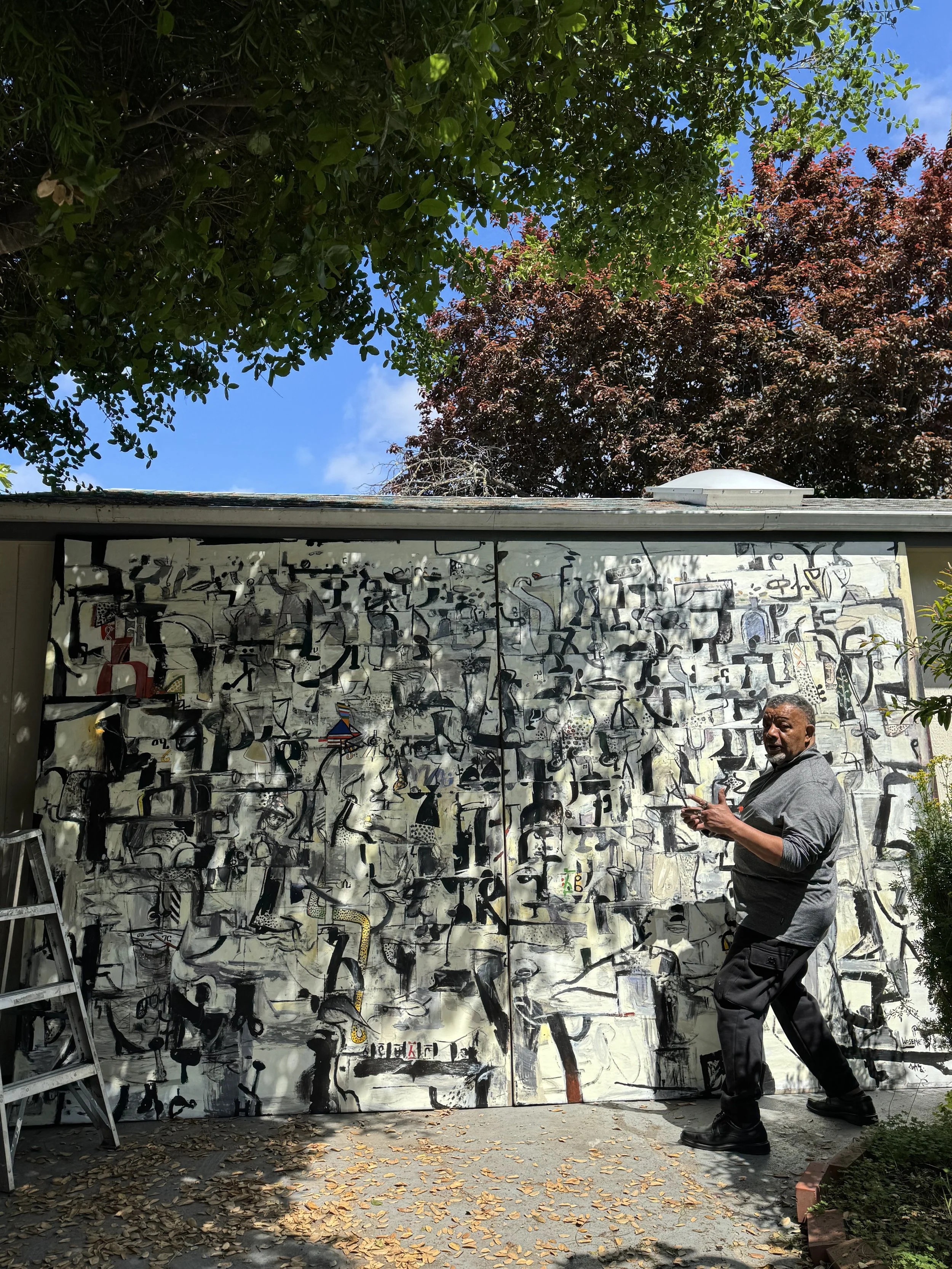Outside his studio in 2025 with the completed painting, For Love of Freedom, 2018.