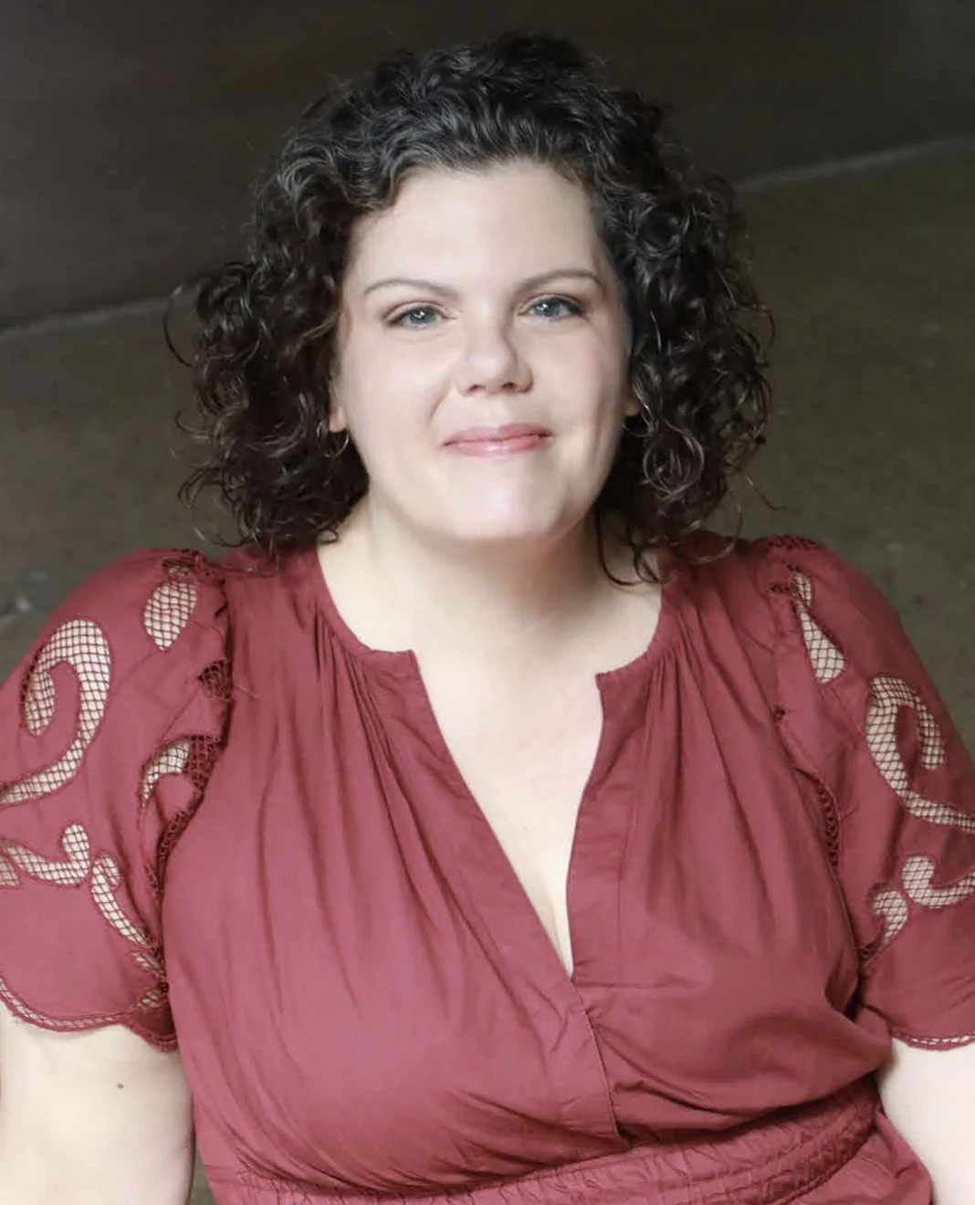 Author Catherine Cicuttini, wearing a red top with lace details on the shoulders, smiling.