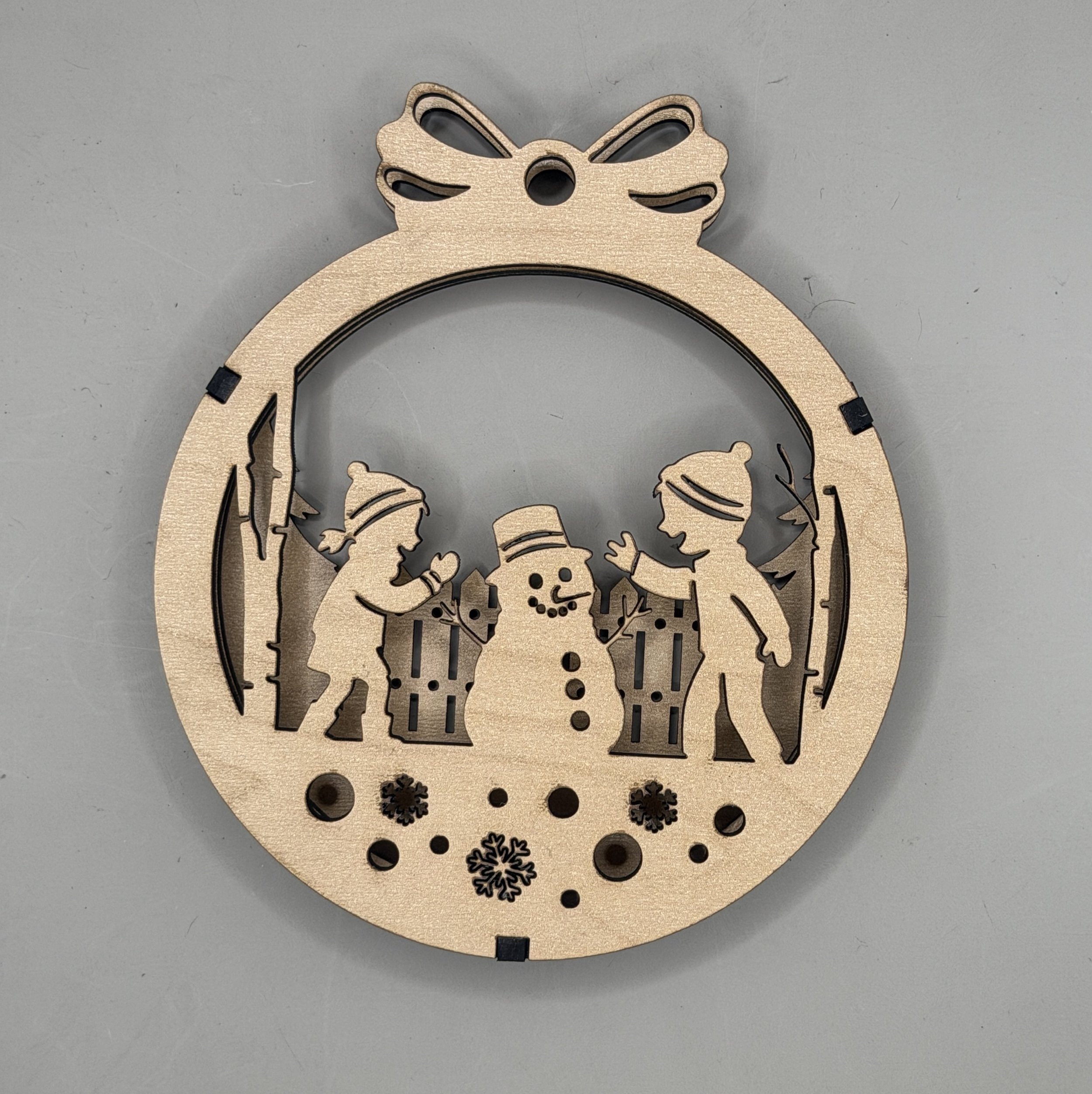 Kids building a snowman layered wood Christmas ornament in maple, front view