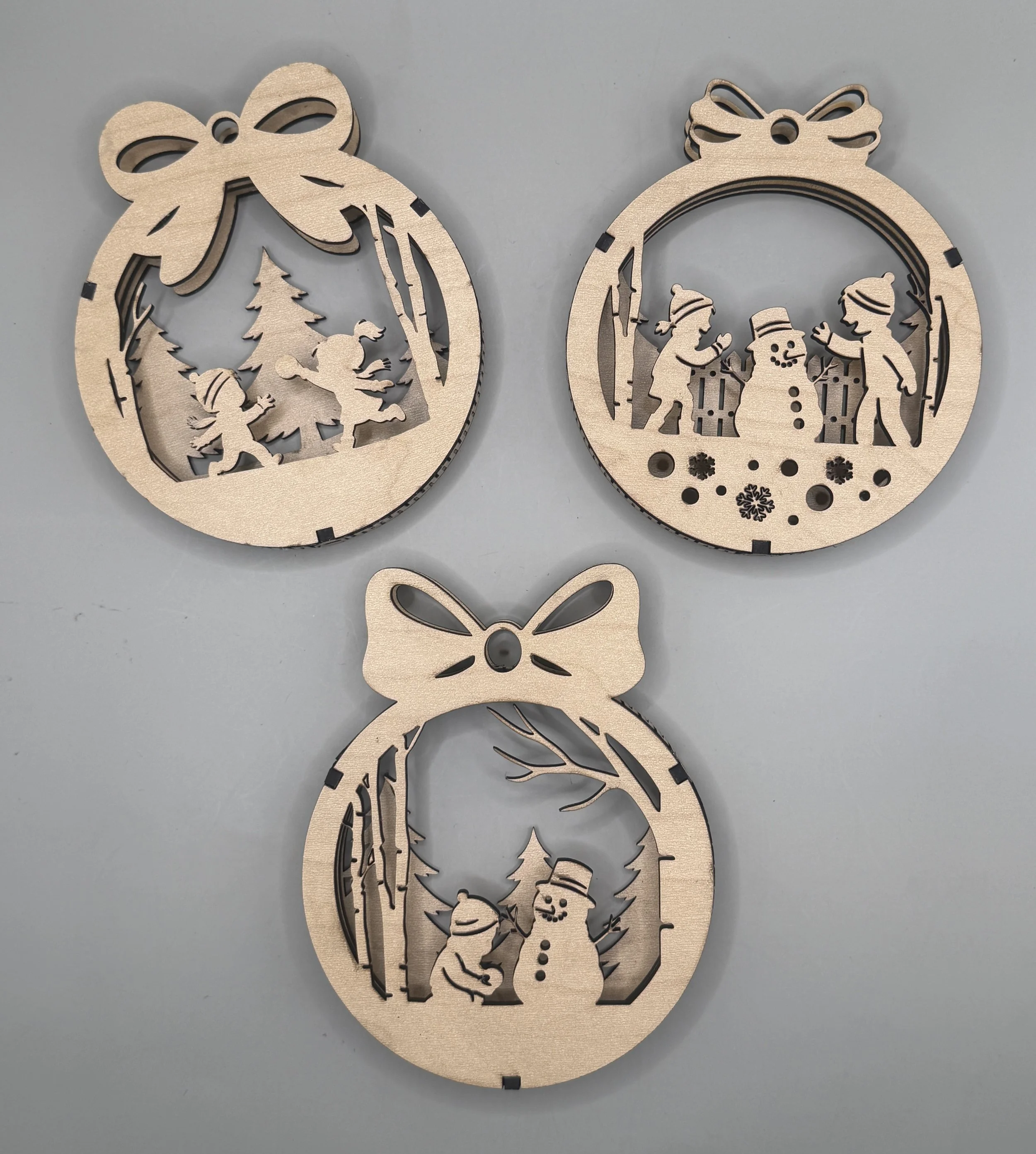 Snow Day layered wood ornament 3-pack in maple: elves, building a snowman and child with snowman