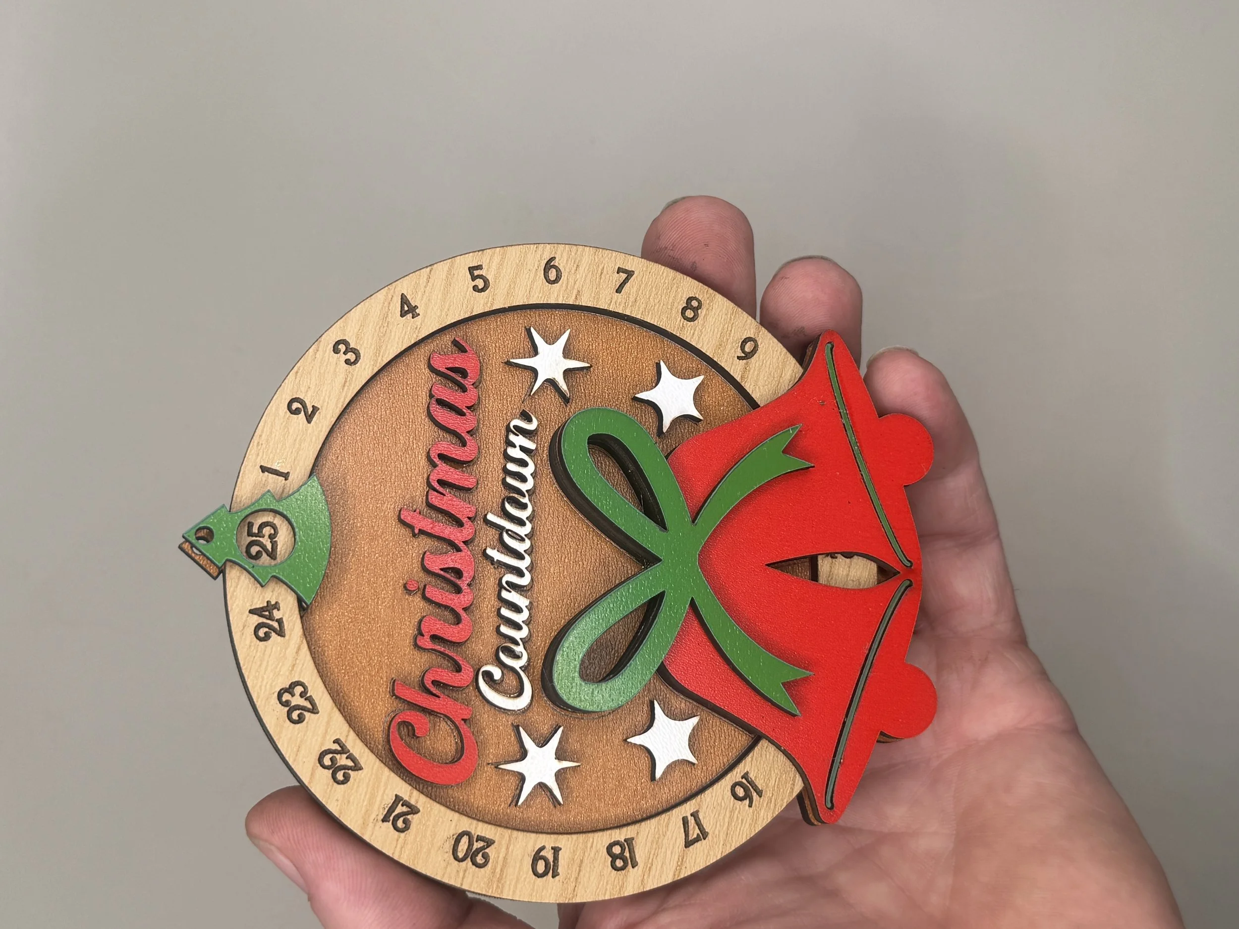 Hand-painted Christmas countdown ornament held in hand to show size