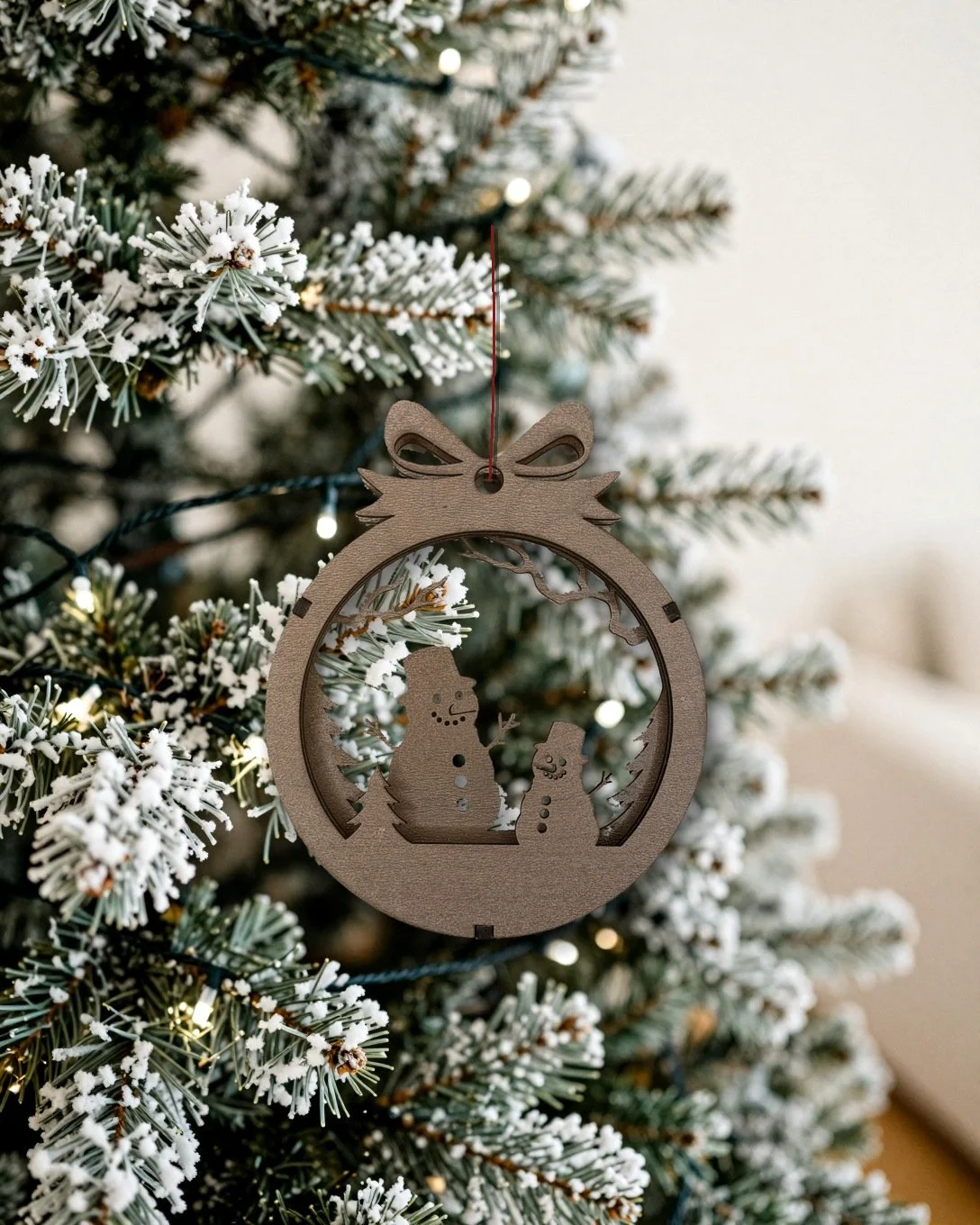 Walnut snowman pair layered wood Christmas ornament hanging on a flocked Christmas tree