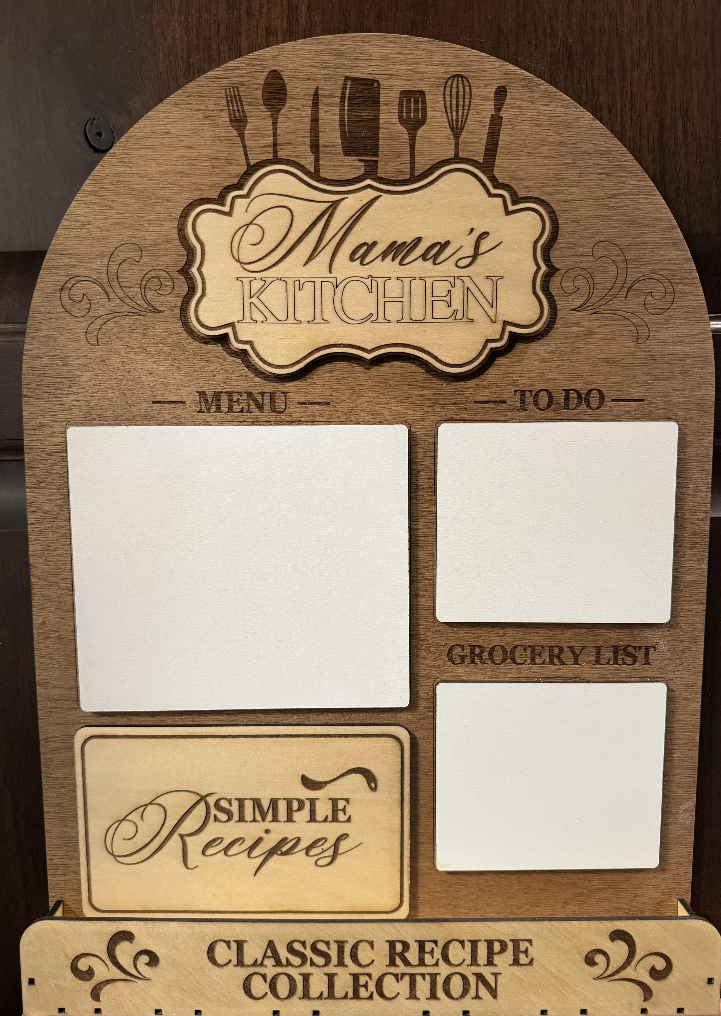 A wooden kitchen signboard with sections for menu, to-do list, grocery list, and simple recipes, labeled 'Mama's Kitchen' at the top, with utensils illustrations at the top and decorative elements.