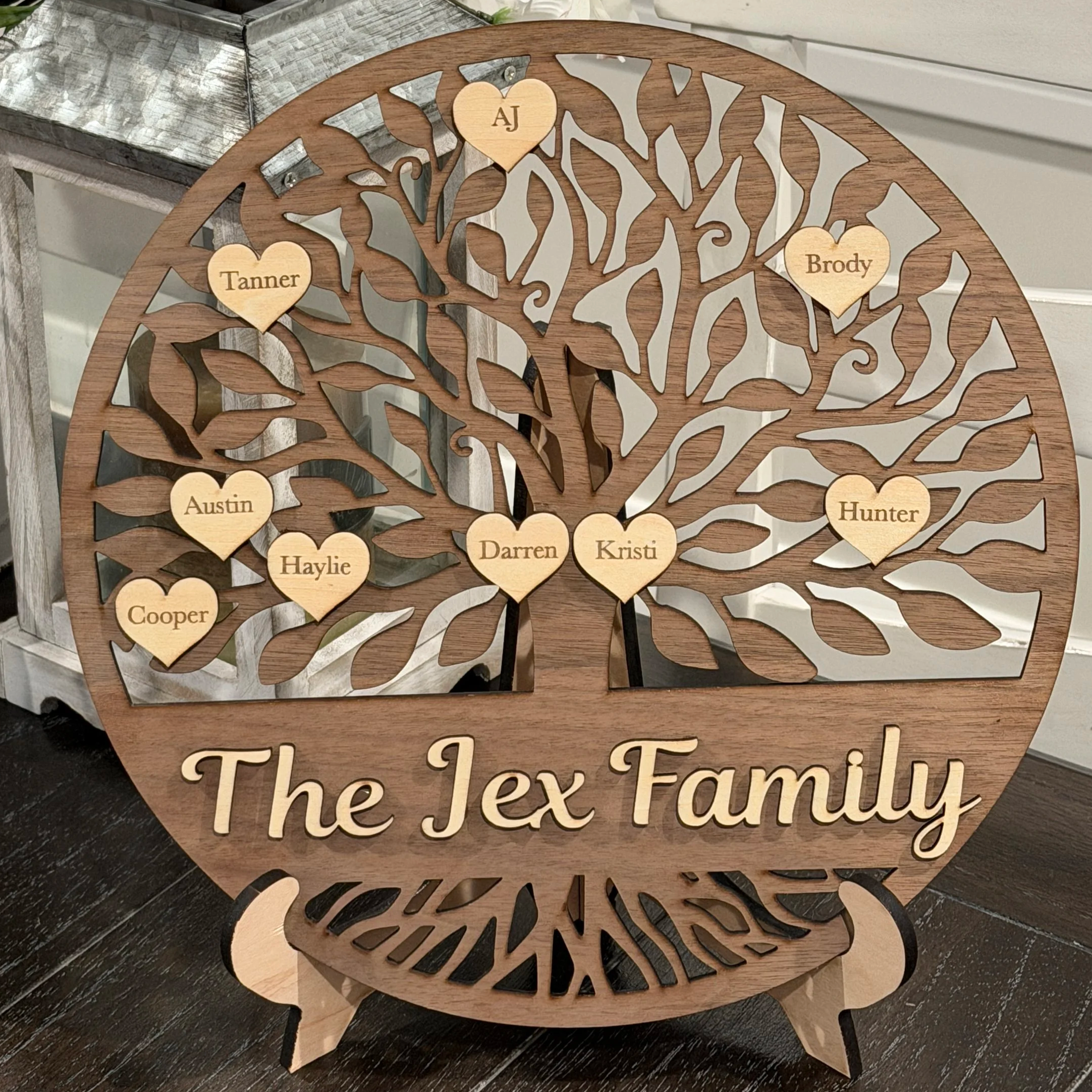 Wooden tree-shaped family sign with heart-shaped name tags and the family name engraved at the bottom.