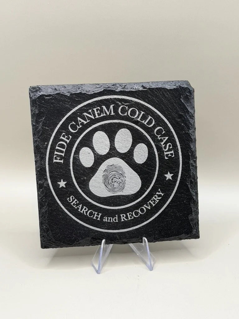 A black stone plaque with a paw print design and the phrase 'FIDE CANEM CANEM CODe' above and 'SEARCH and RECOVERY' below.