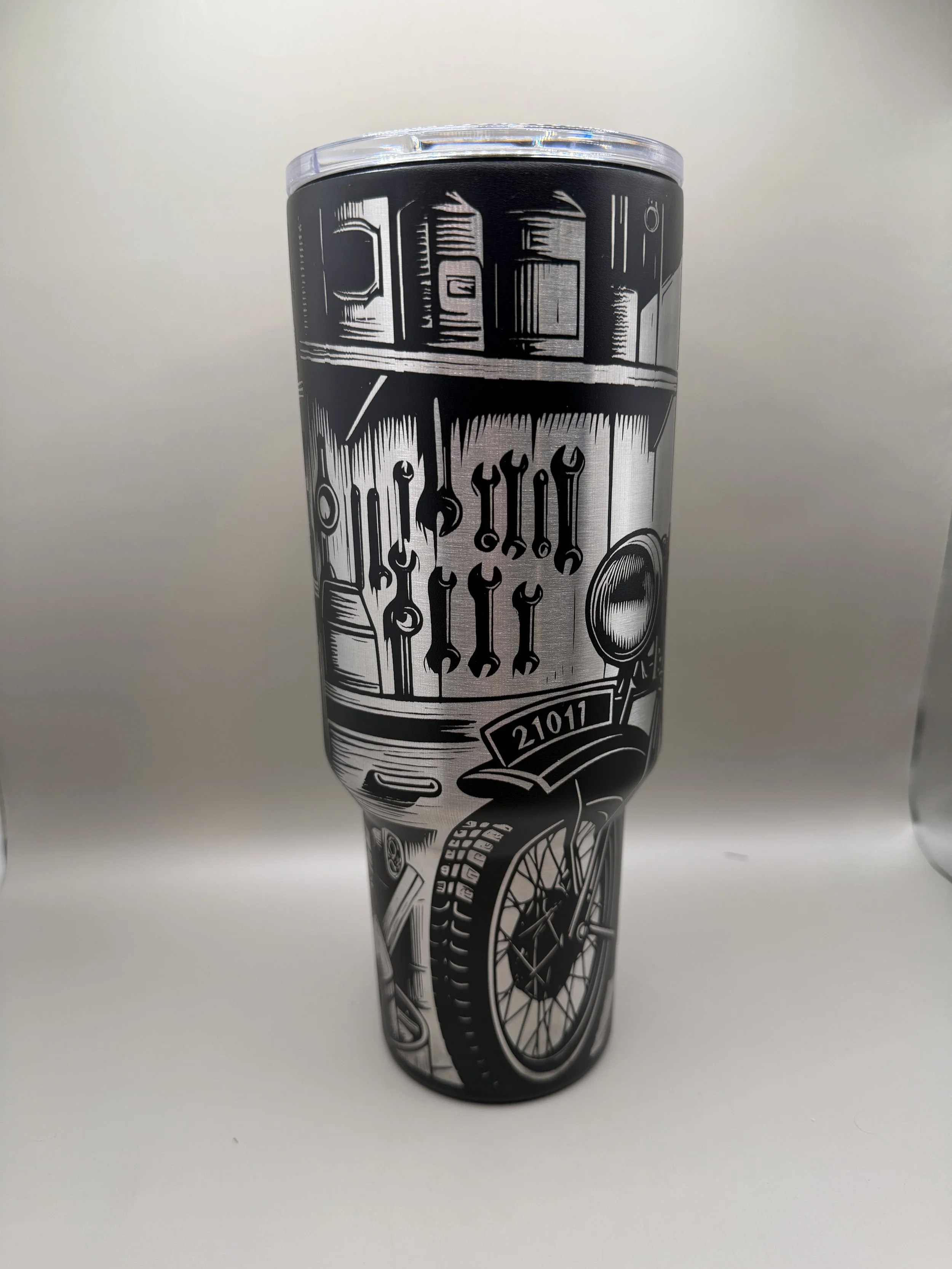 A black and white tumbler featuring illustrations of tools, a bicycle wheel, and various mechanical objects.